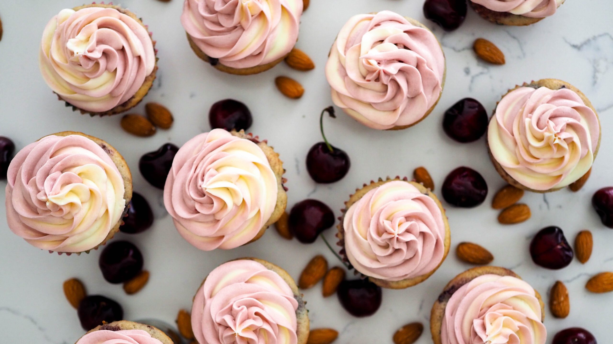 Cherry almond cupcakes amid cherries and almonds.