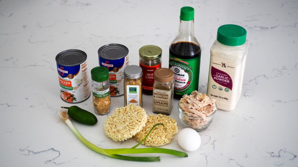 The ingredients for chicken ramen on a white quartz counter.