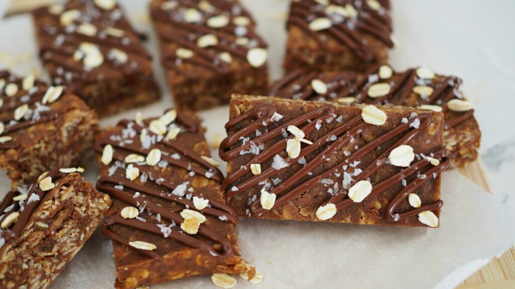 No-bake chocolate protein granola bars are arranged on parchment paper.