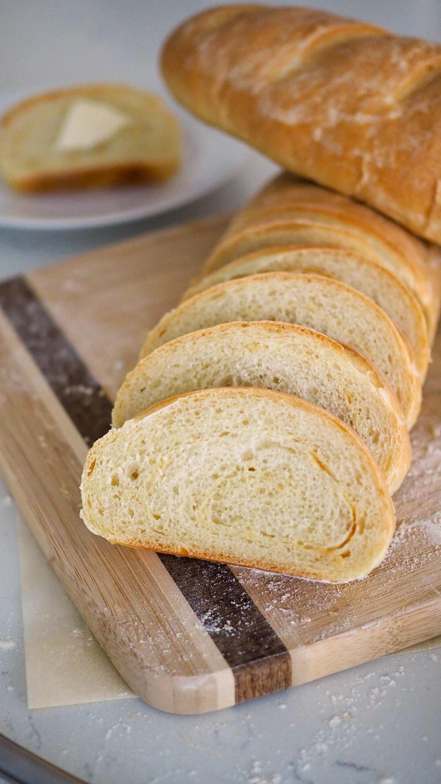 A sliced loaf of garlic French bread with another loaf resting on top of it.
