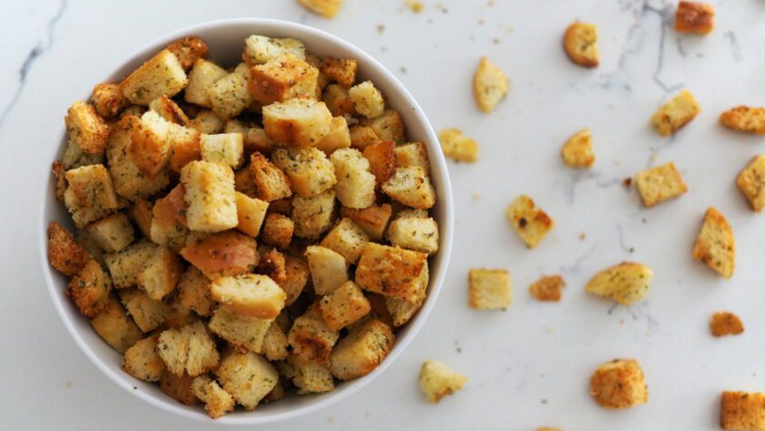 A bowl full of croutons, with some arranged on a white quartz counter.