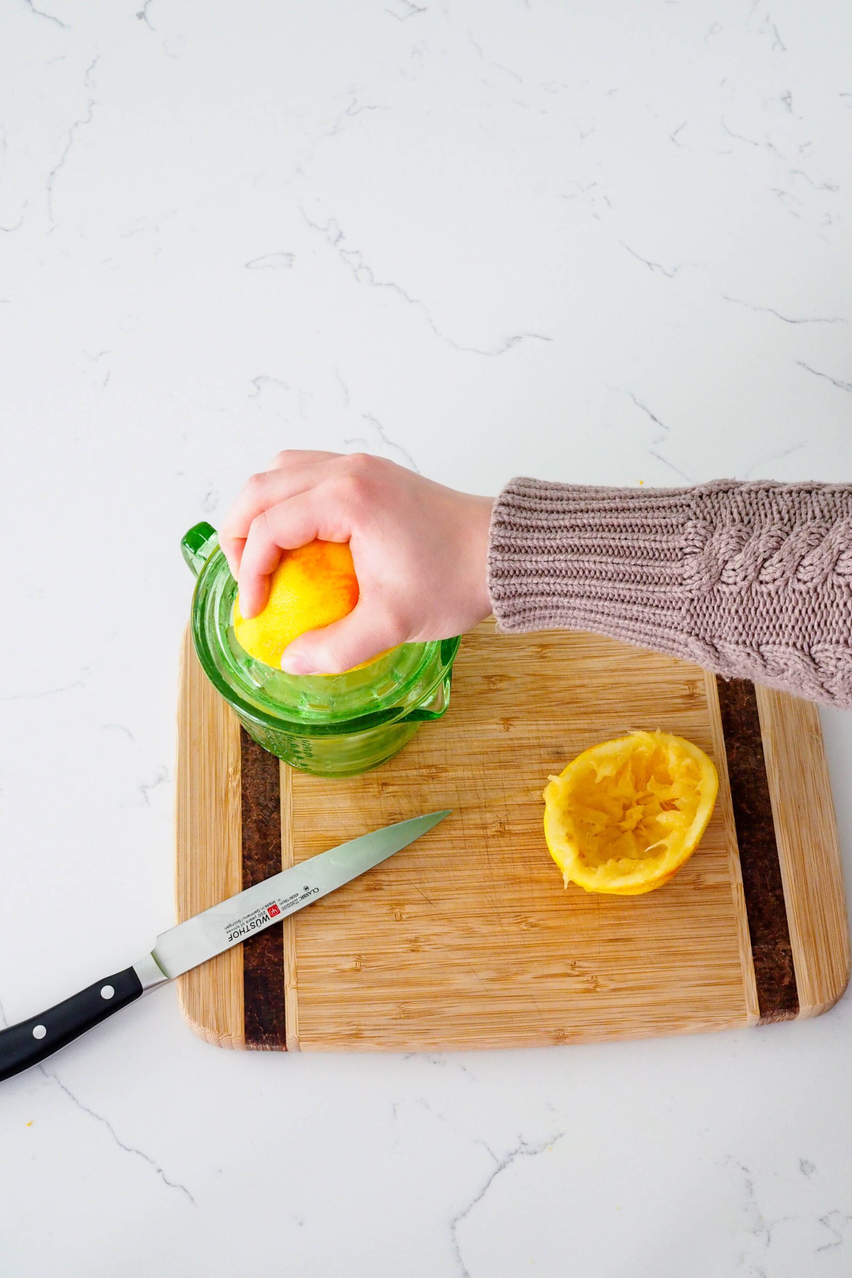 A hand squeezes fresh orange juice.