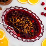 An overhead shot of cranberry orange sauce with orange slices and cranberries around it.