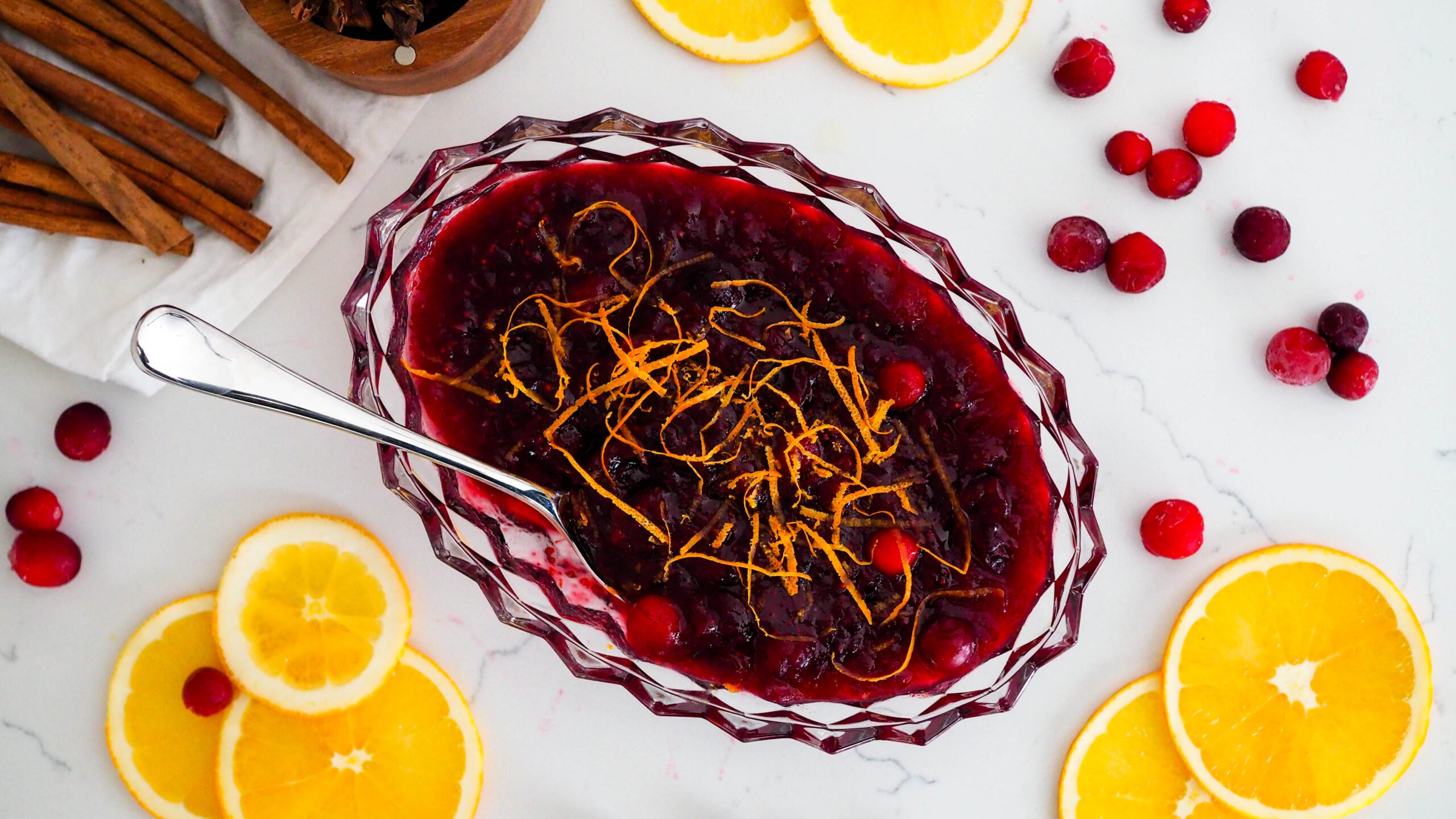 An overhead shot of cranberry orange sauce with orange slices and cranberries around it.