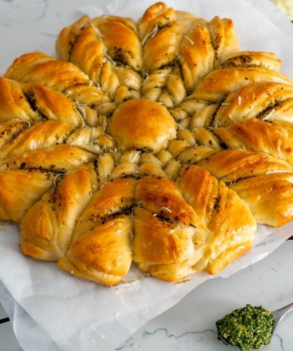 A layered loaf of bread is in the shape of a star, filled with pesto and parmesan.