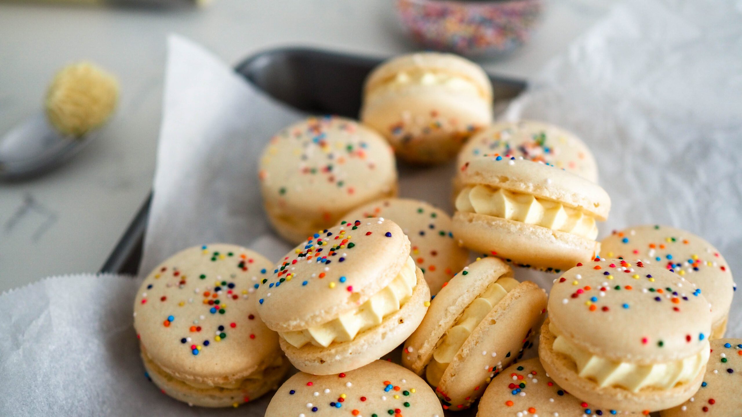 A pile of birthday cake macarons topped with sprinkles.