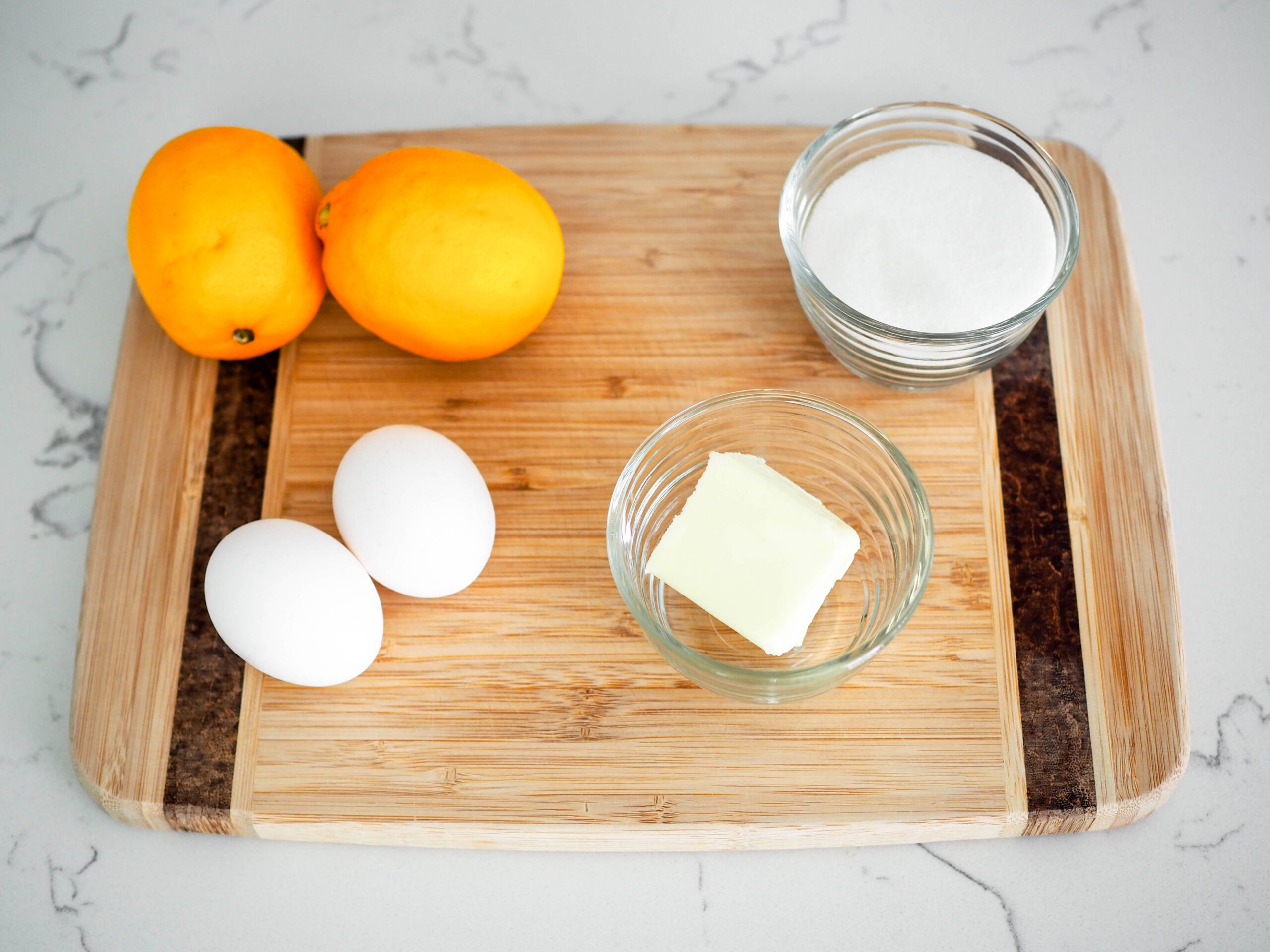 Ingredients for small batch lemon curd arranged on a wooden cutting board.
