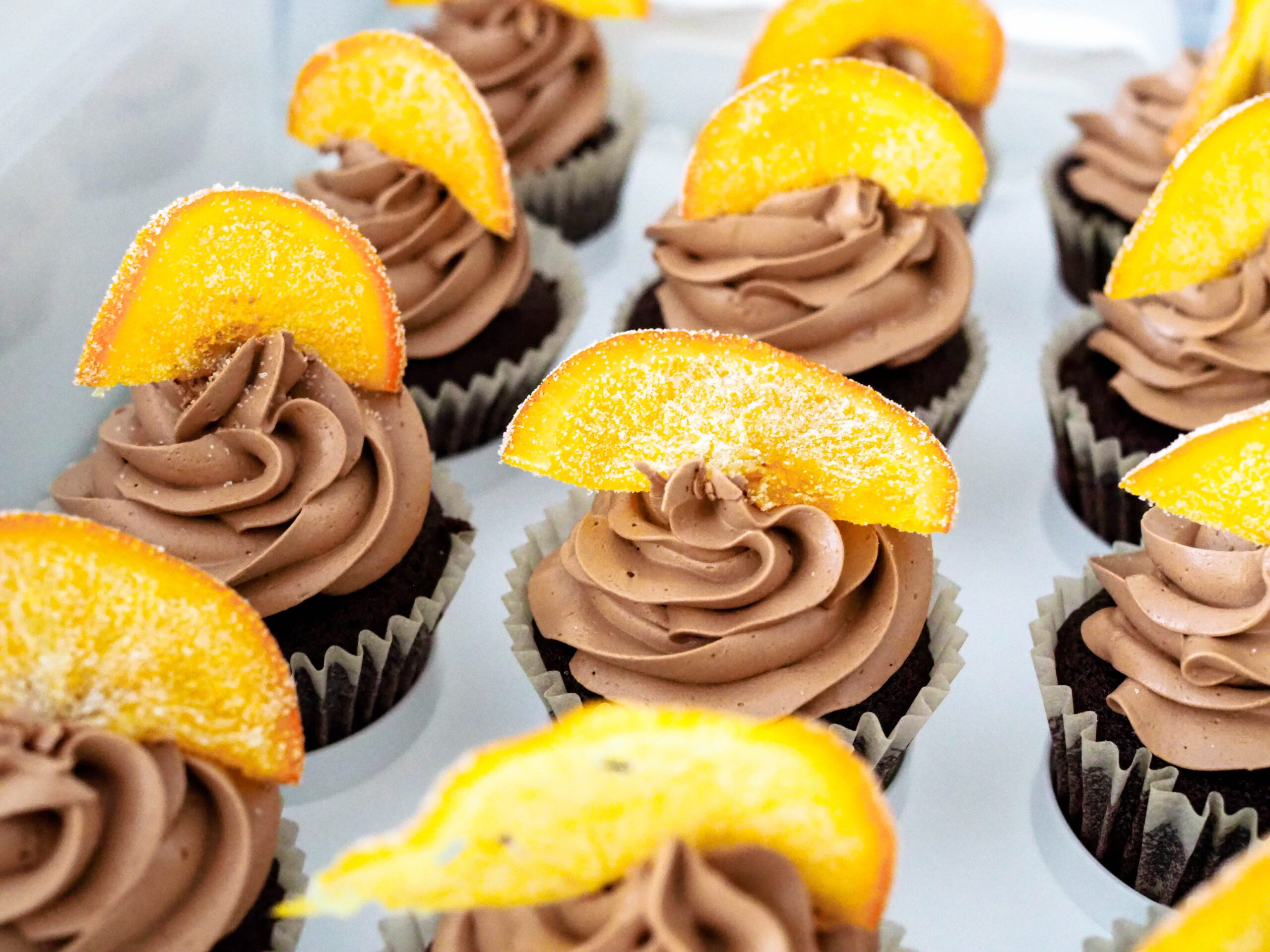 Gluten-free, dairy-free chocolate orange cupcakes with a candied orange on top of a swirl of chocolate French buttercream.