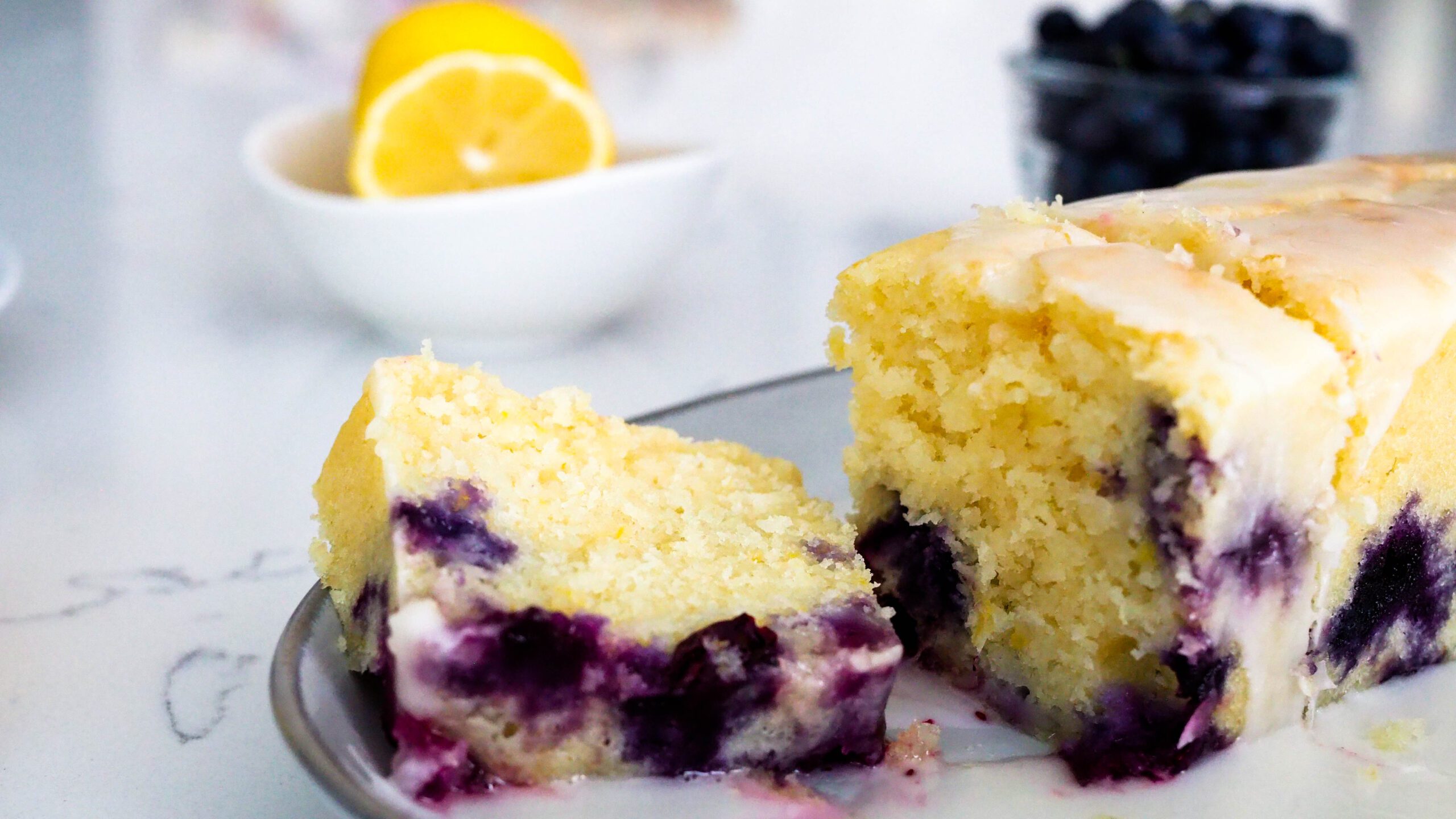 A slice of lemon blueberry loaf cake on a gray stoneware platter.