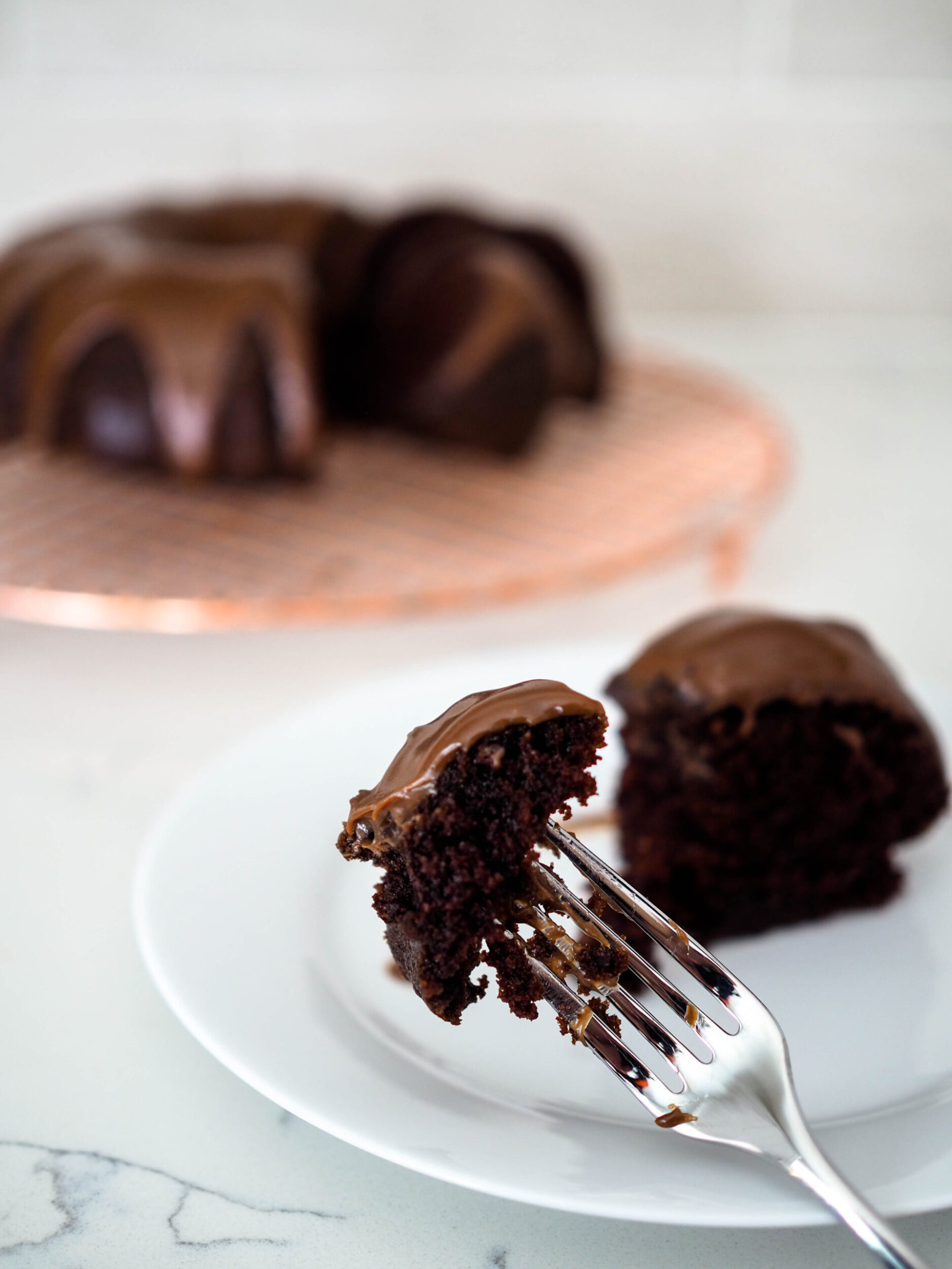 A fork holds up a moist-looking bite of chocolate Bundt cake.