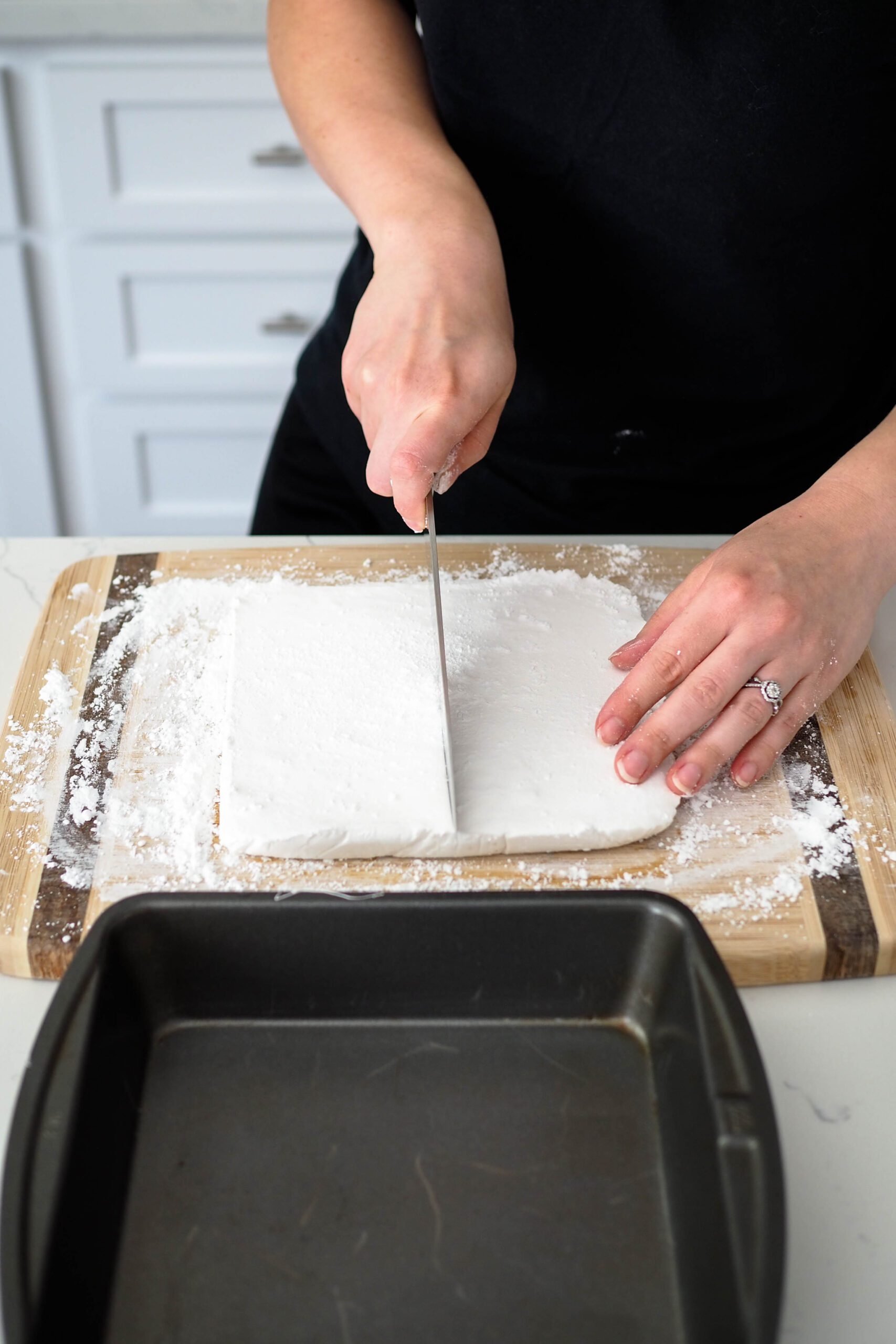 A homemade marshmallow loaf is cut in half with a sharp knife.