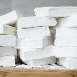 A stack of marshmallows on a wooden cutting board.