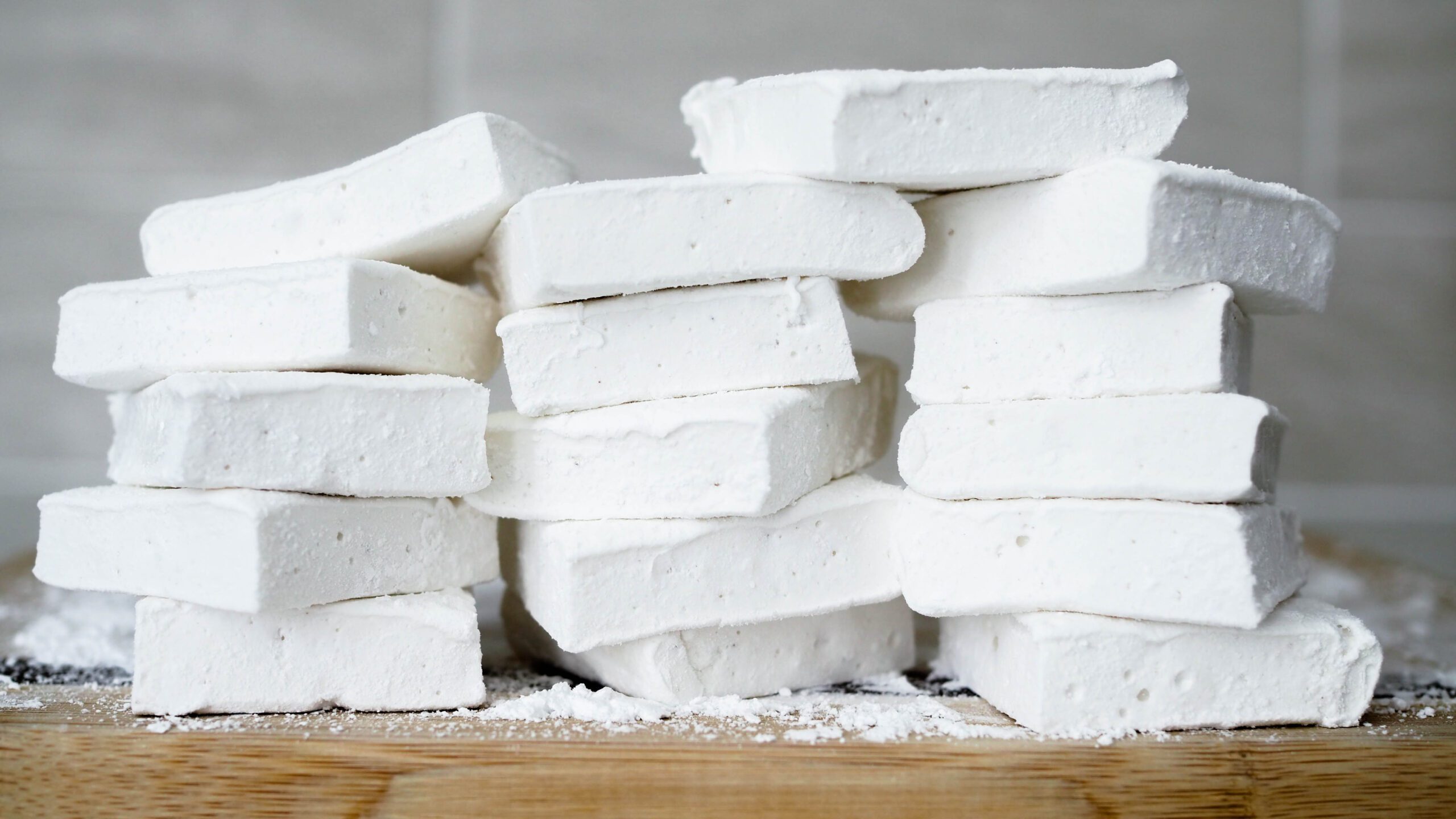 A stack of marshmallows on a wooden cutting board.