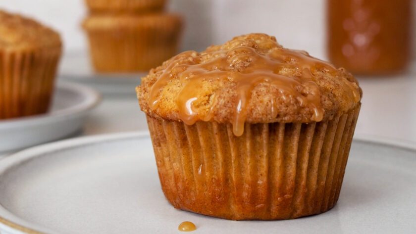 A caramel chai muffin on a gray plate with other muffins in the background.