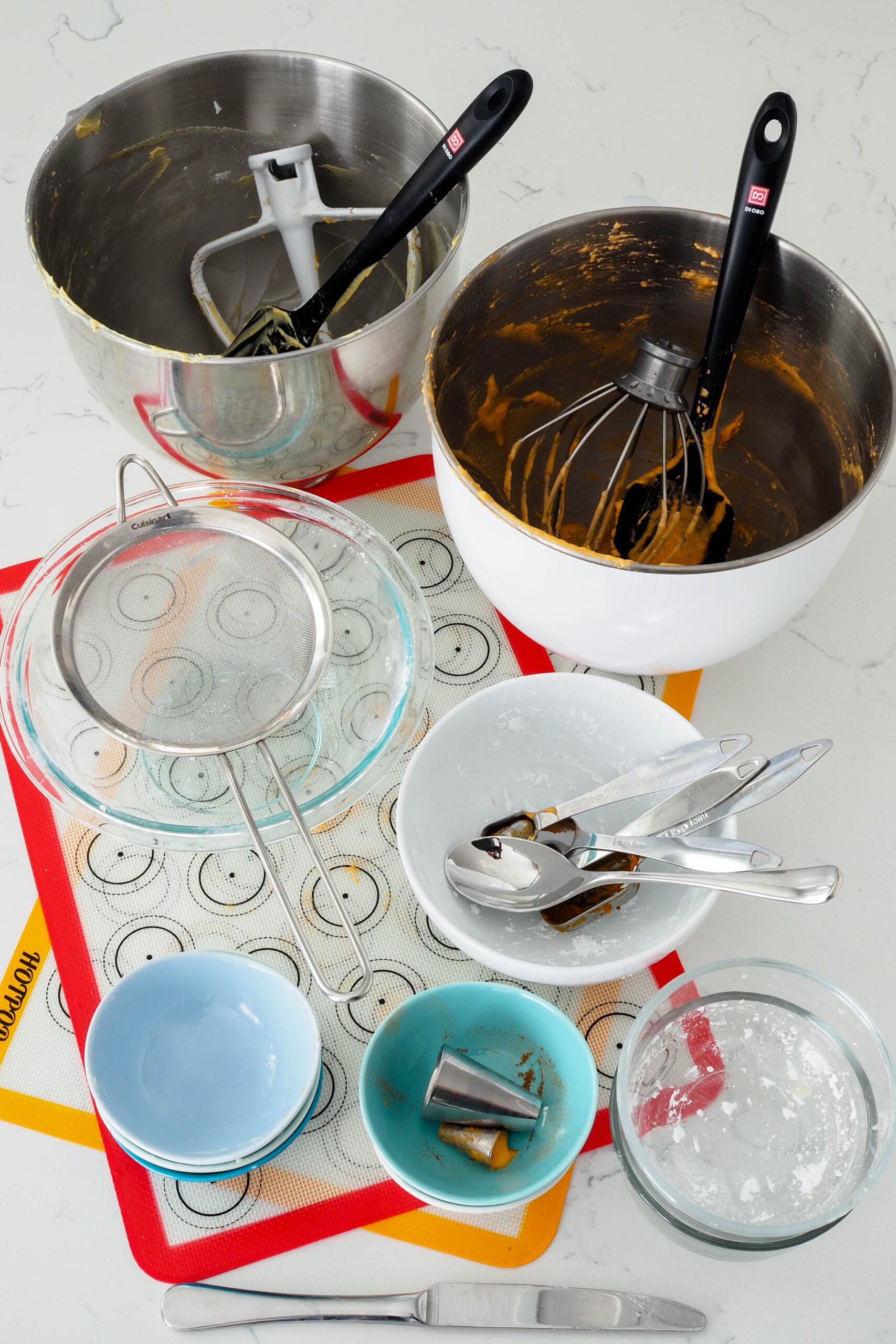 A collection of dishes and utensils used to make pumpkin spice macarons.