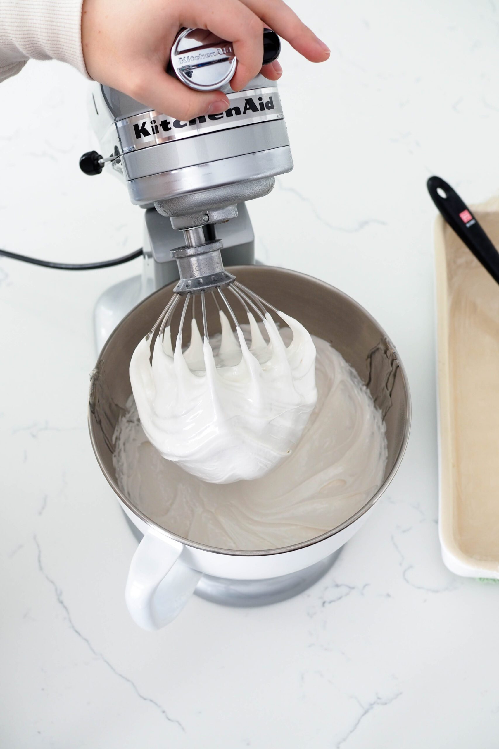Marshmallow is clumped into the base of the whisk of a stand mixer.