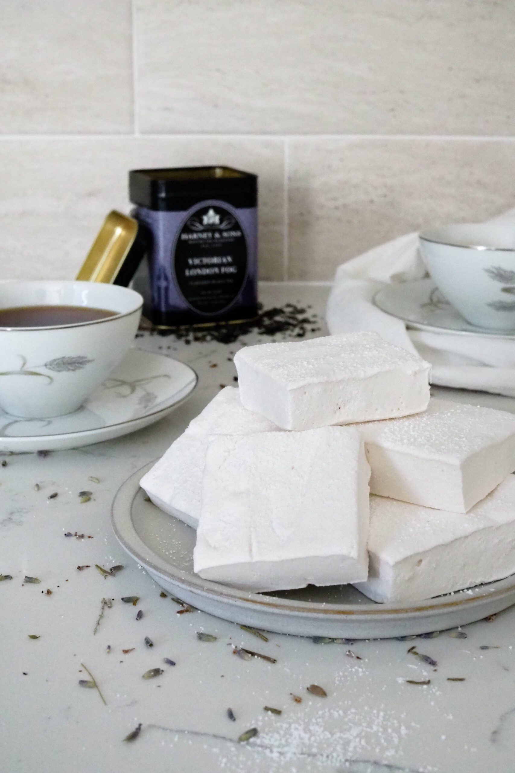 A pile of homemade Earl Grey marshmallows by a cup of tea and Harney and Sons tea container.