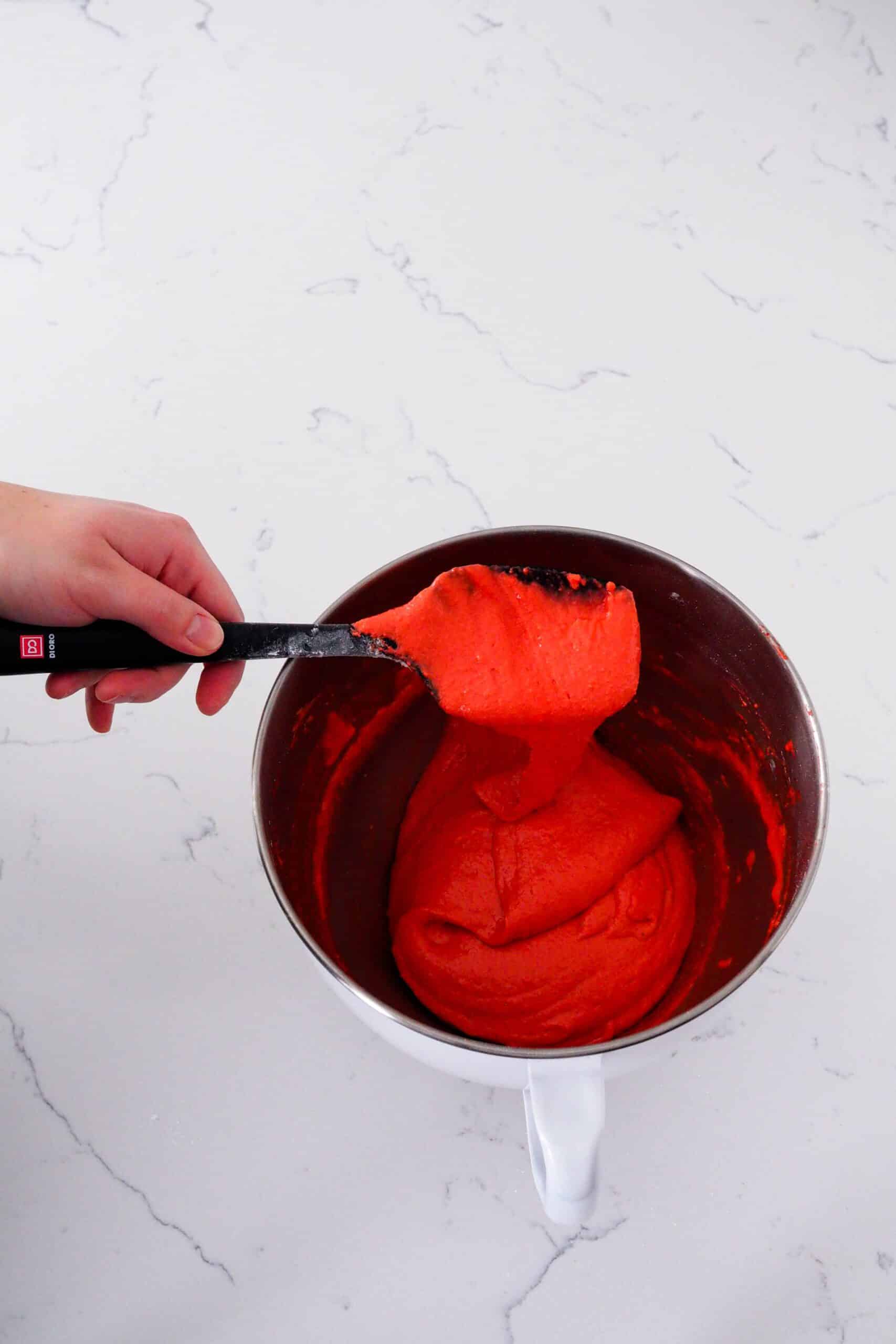 Macaron batter flows off a spatula in a long ribbon.