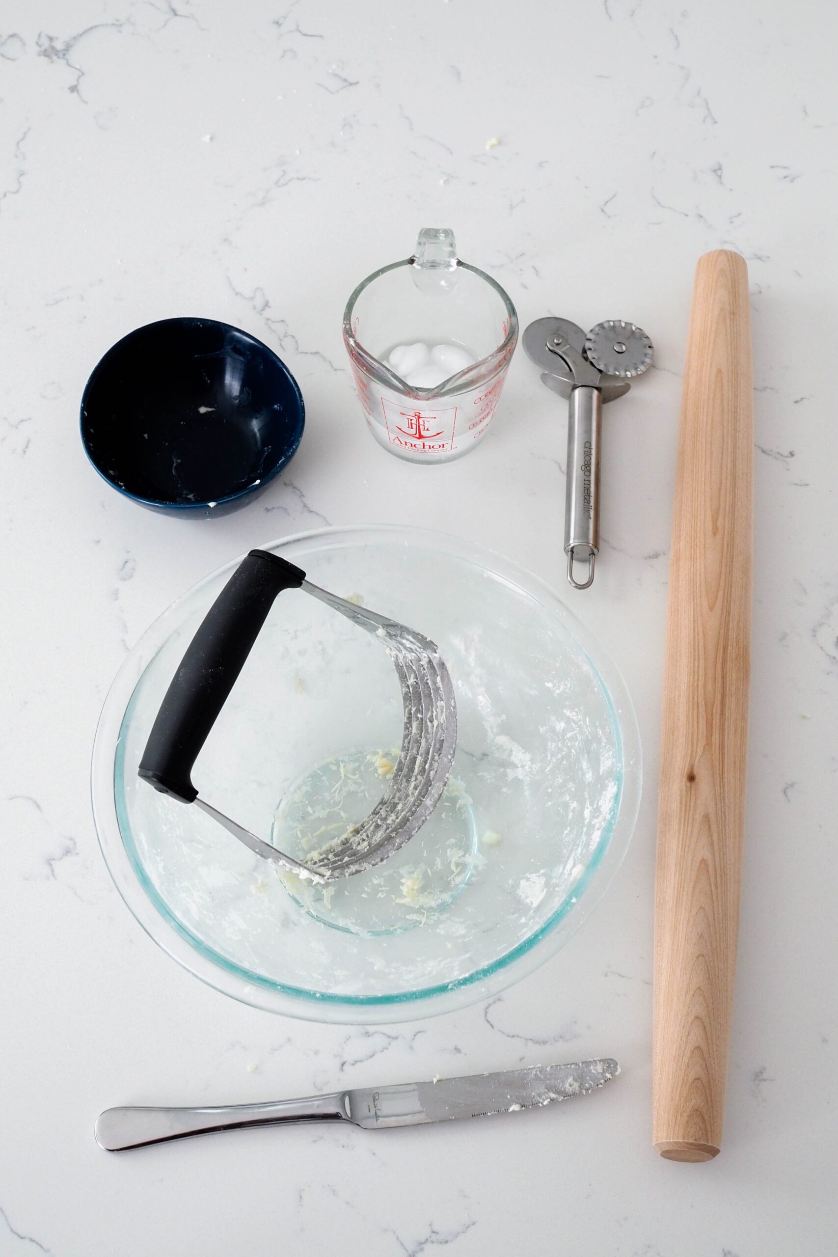 A large bowl, a rolling pin, and some smaller dishes on a white quartz counter.