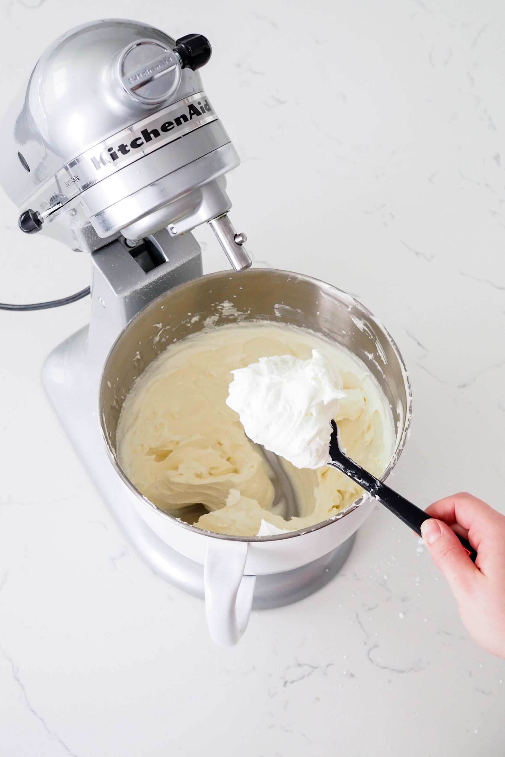 White chocolate buttercream is light and fluffy on a spatula.