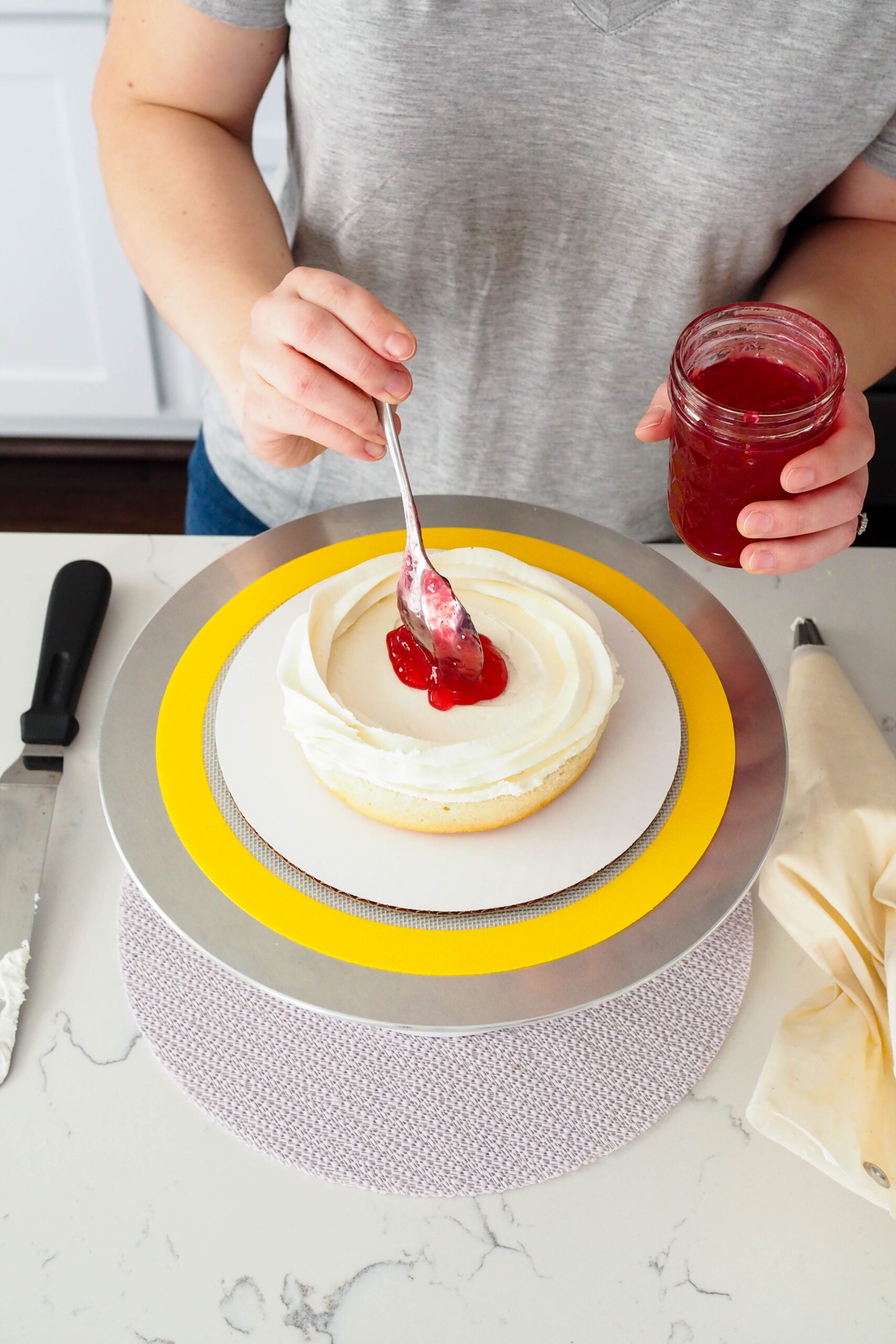 Pomegranate jelly is spooned into the center of a white cake layer with a ring of white chocolate buttercream around it.
