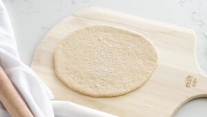 A pizza dough round on a pizza peel.