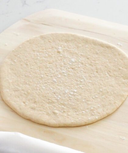 A pizza dough round on a pizza peel.