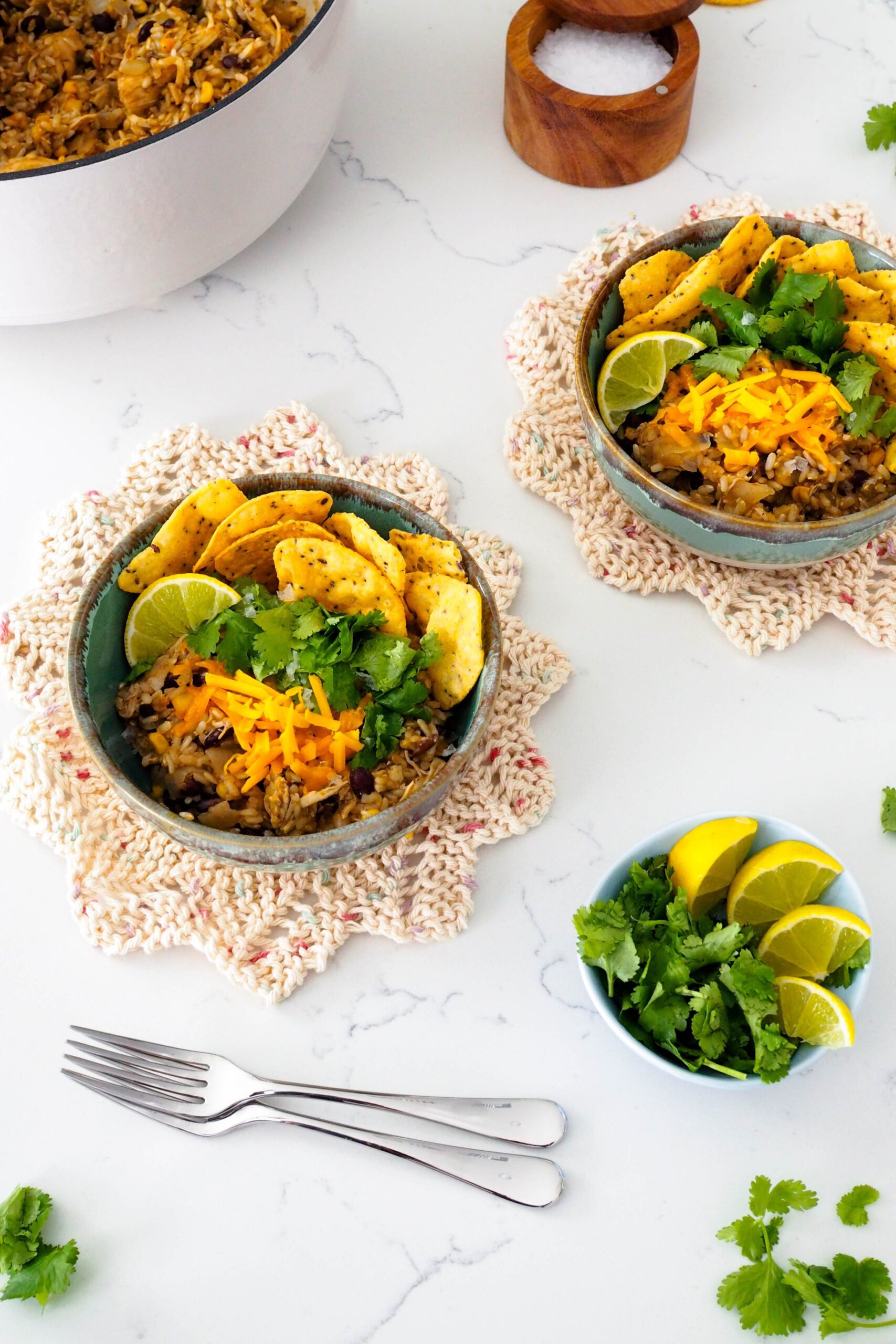 Two bowls of one-pot chicken and brown rice with various toppings.