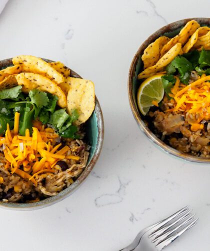 Two bowls of one-pot chicken and brown rice with toppings.