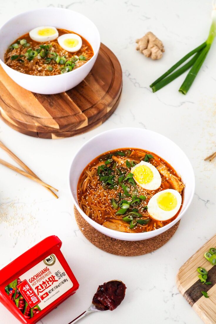 Two bowls of gochujang chicken ramen are on a white counter.