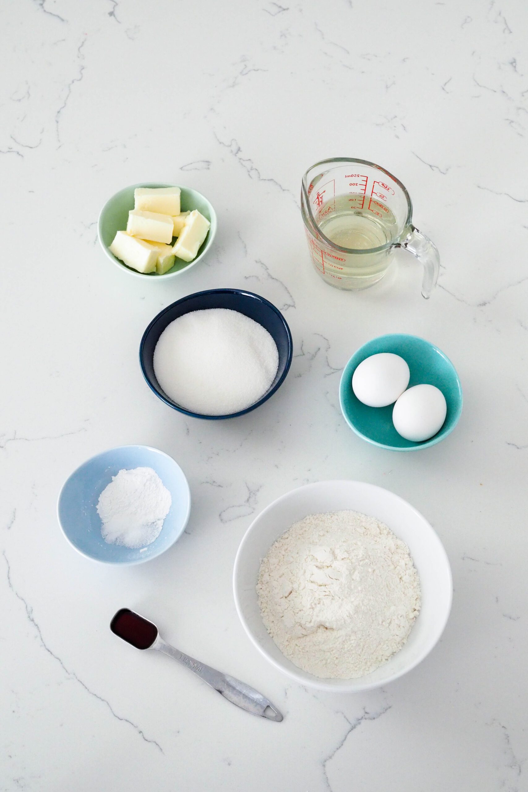 Ingredients needed to make the champagne cupcakes on a white quartz counter.
