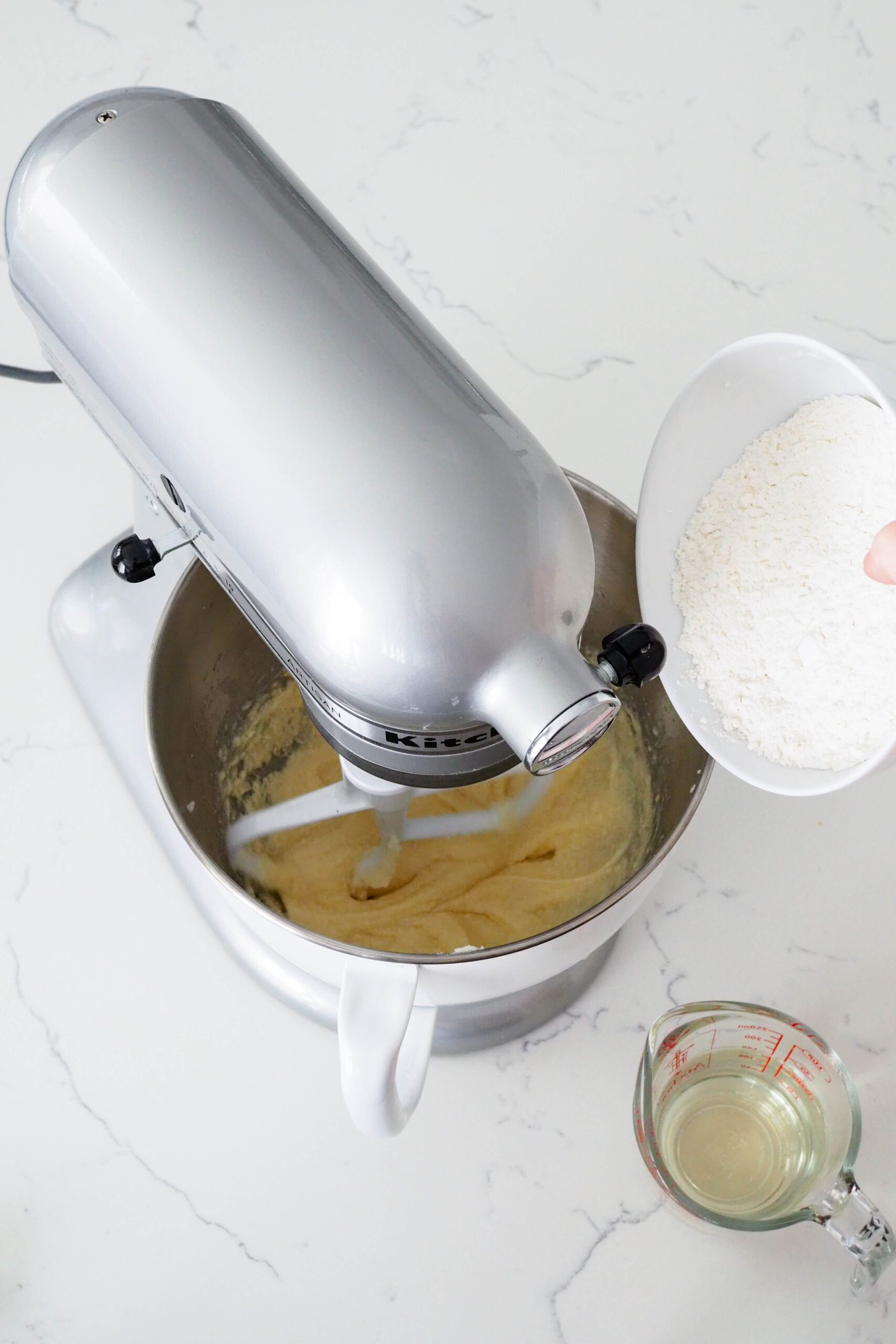 A bowl of flour hovers over a stand mixer.