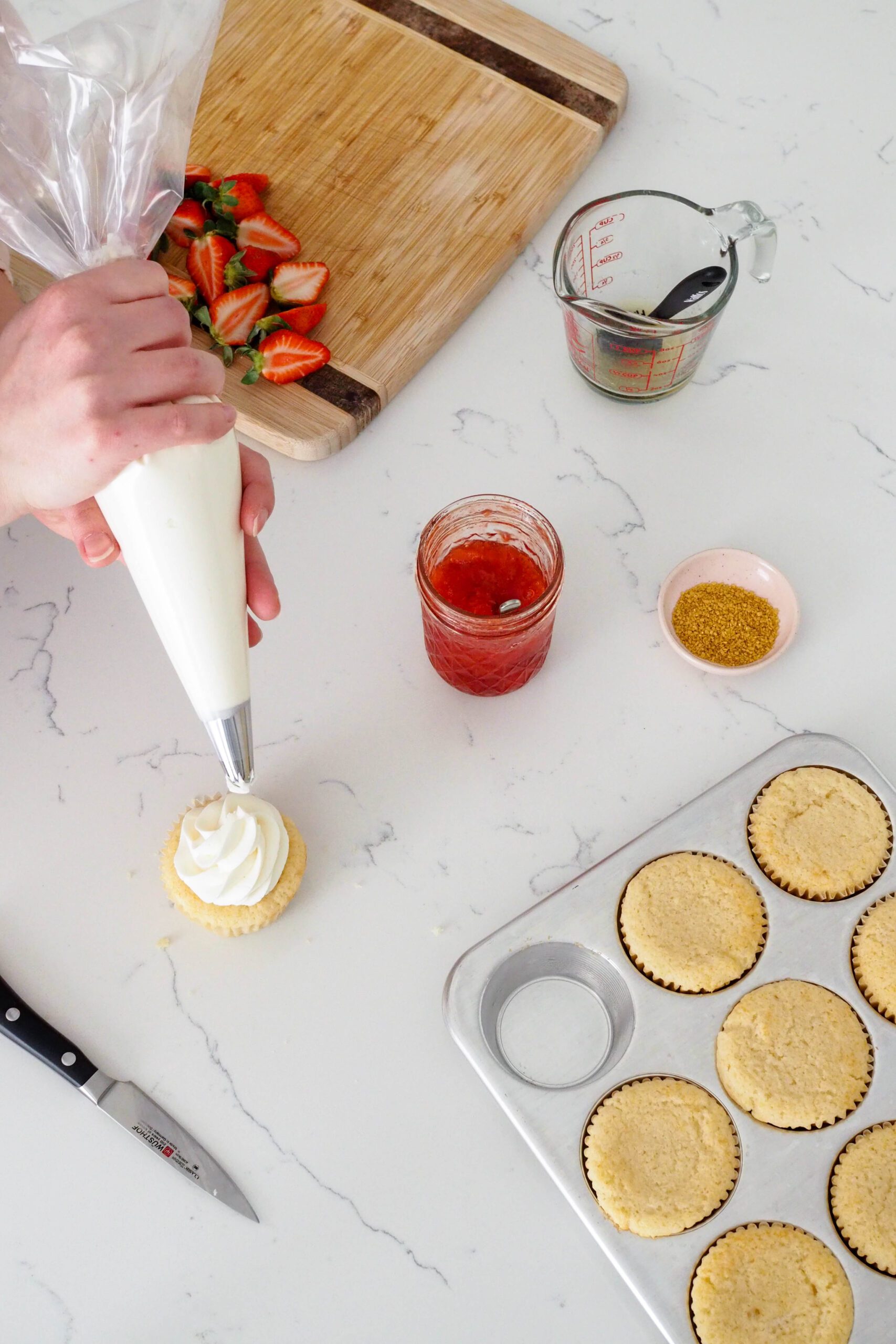 Champagne buttercream is piped on top of a strawberry champagne cupcake.