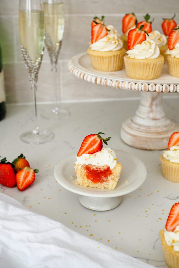 A strawberry champagne cupcake is cut in half to reveal a strawberry champagne jam center.
