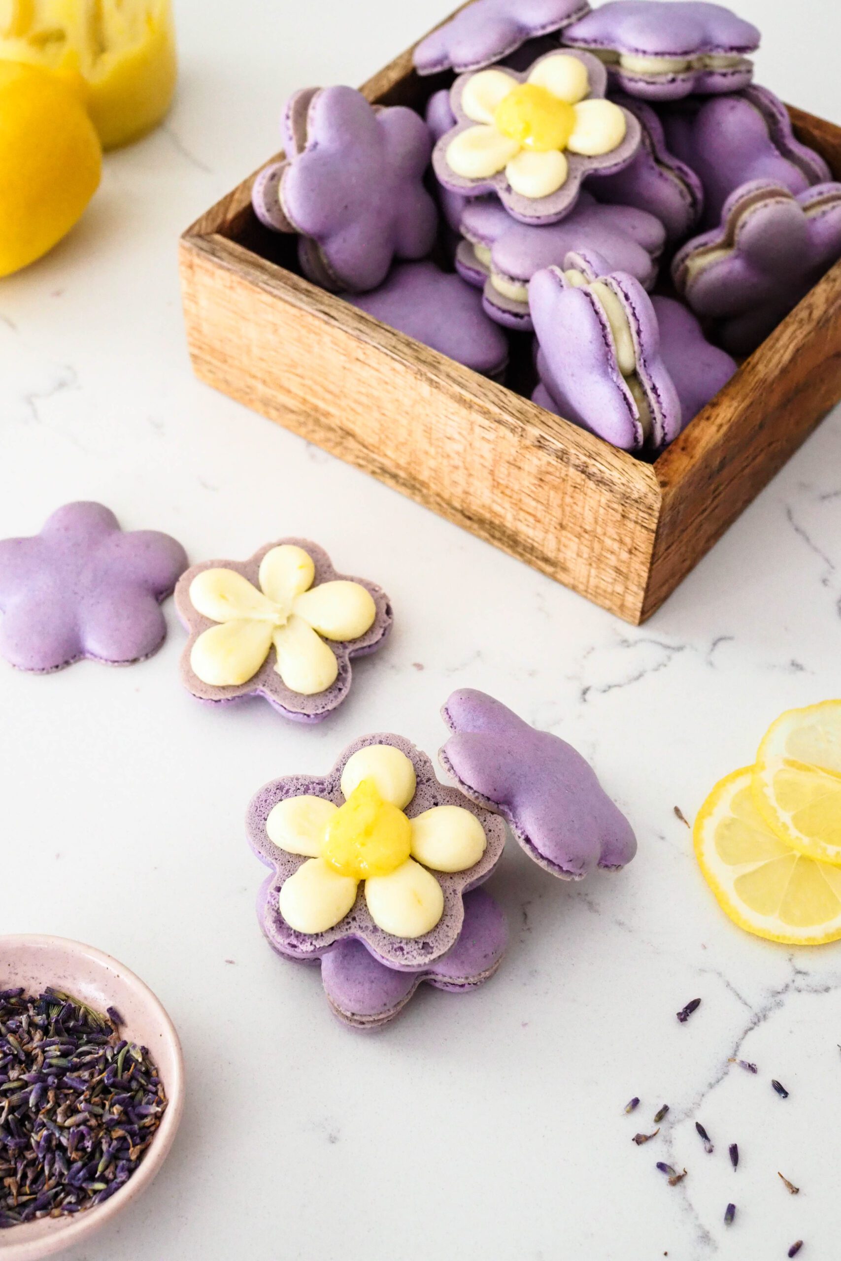 A collection of flower-shaped lemon lavender macarons on a quartz counter.