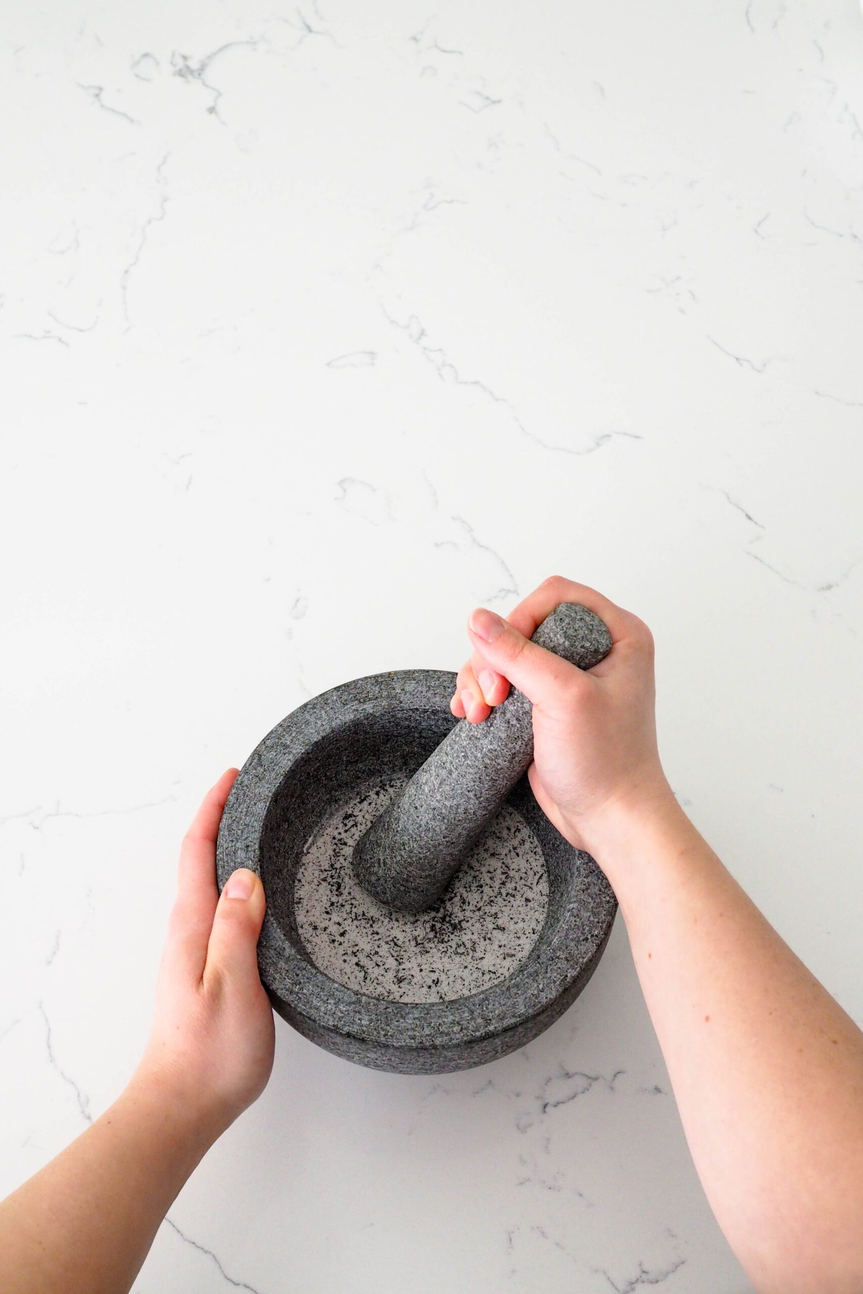 A hand grinds Earl Grey tea and sugar in a mortar and pestle.