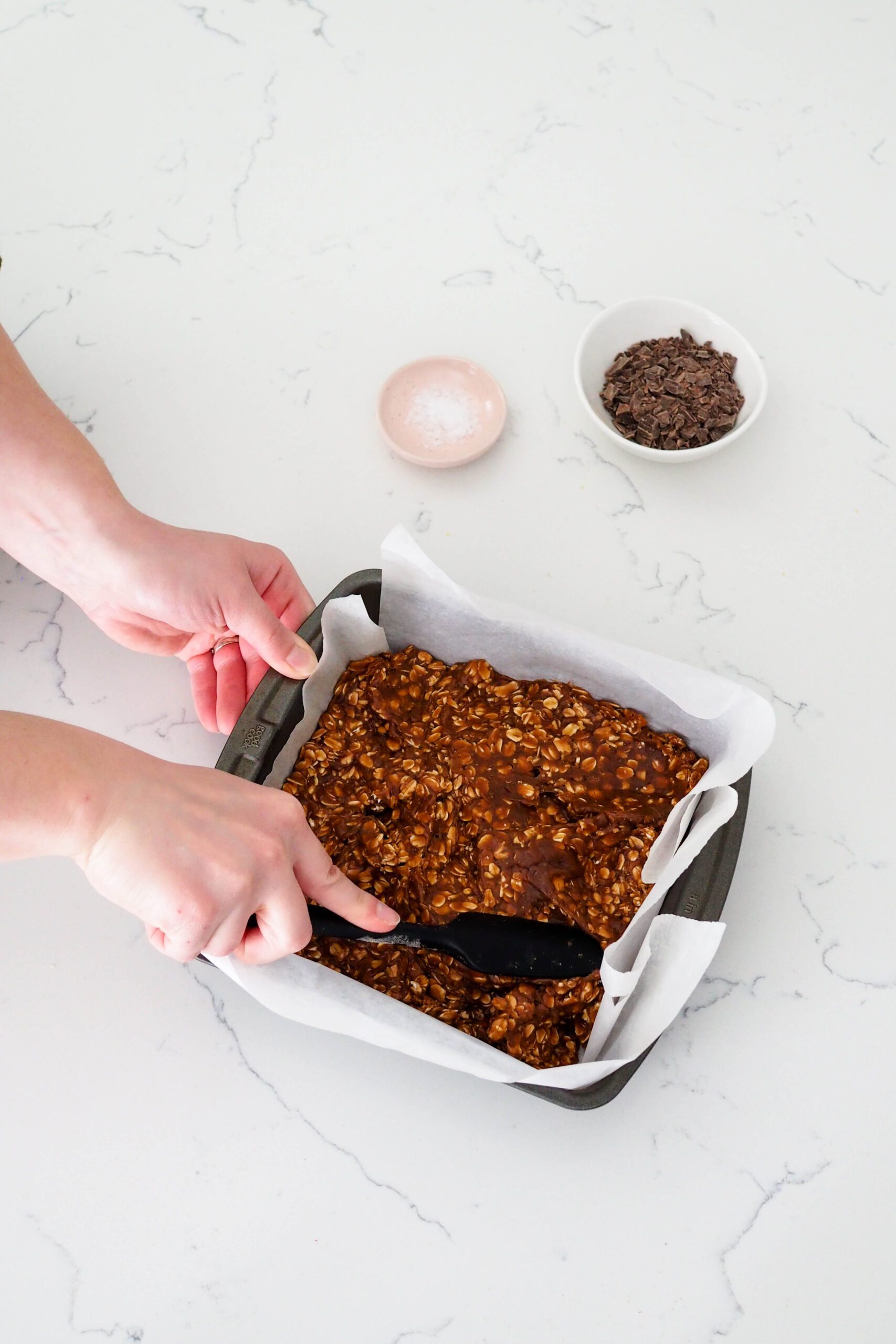 A spatula presses the protein bars into the pan.