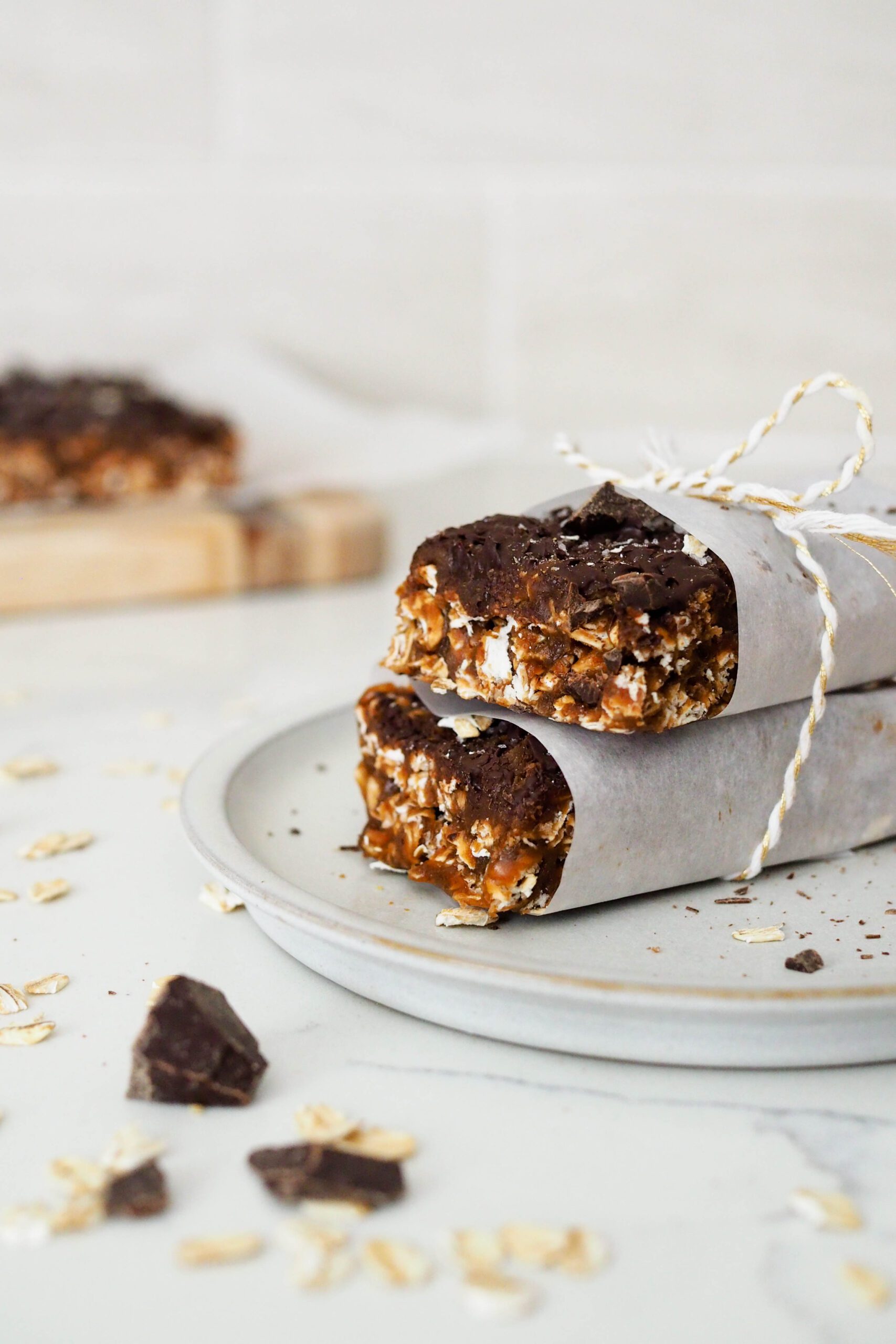 Two homemade protein granola bars wrapped in parchment and tied together with a string.