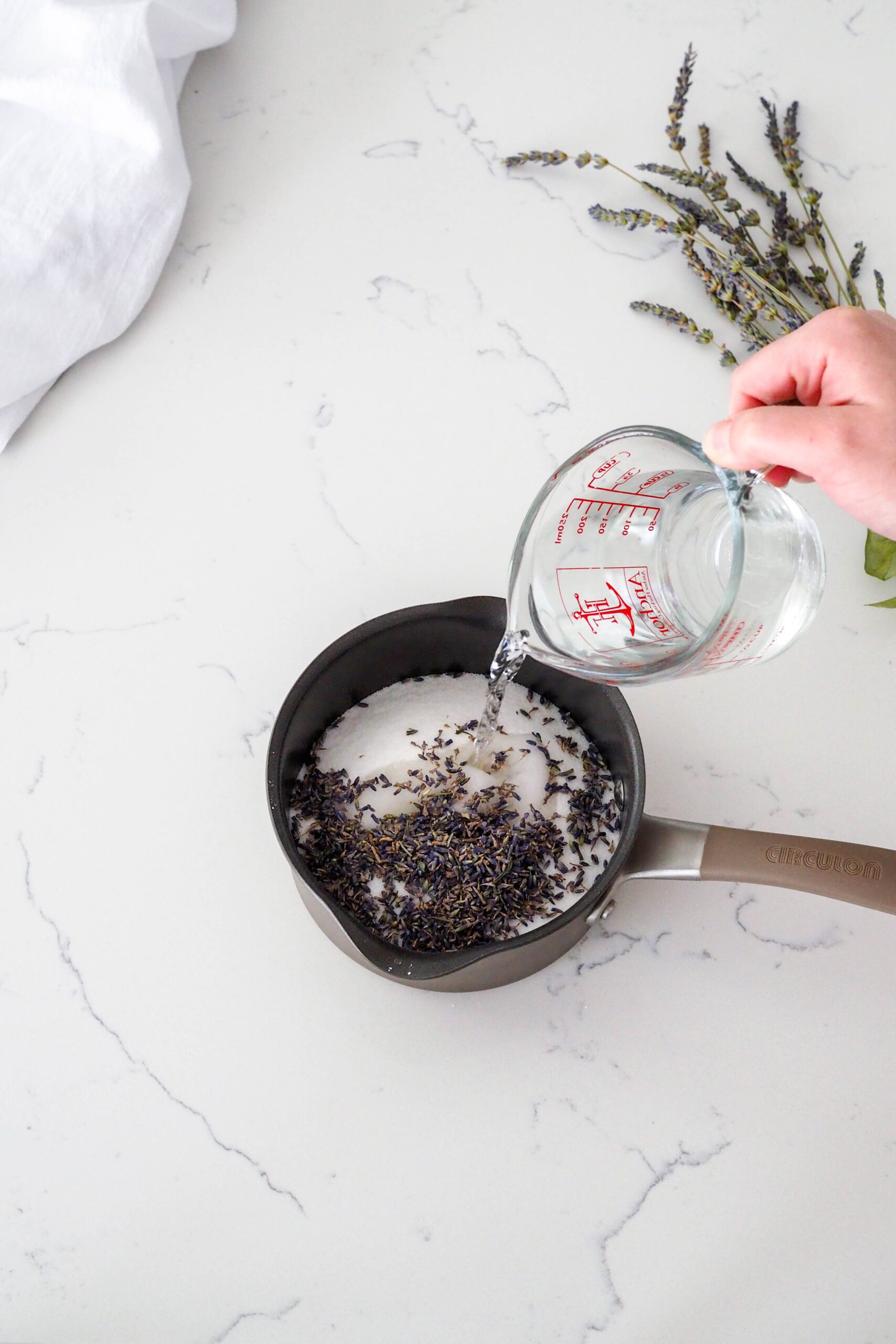 Water is poured over sugar and lavender buds in a small saucepan.