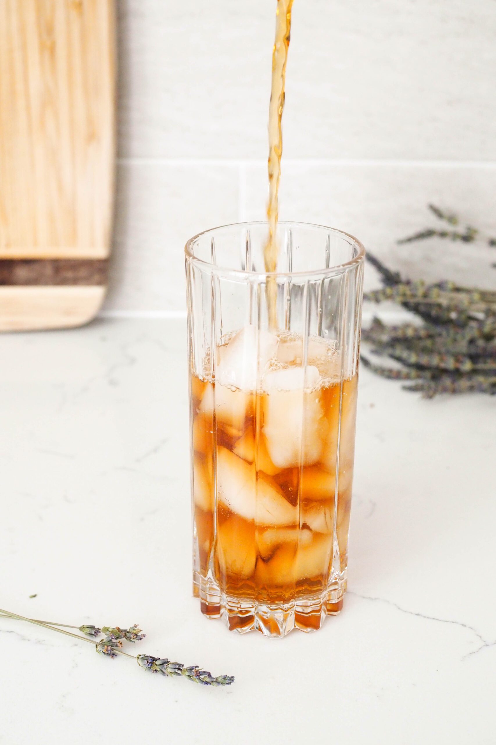 Tea is poured over ice in a highball glass.