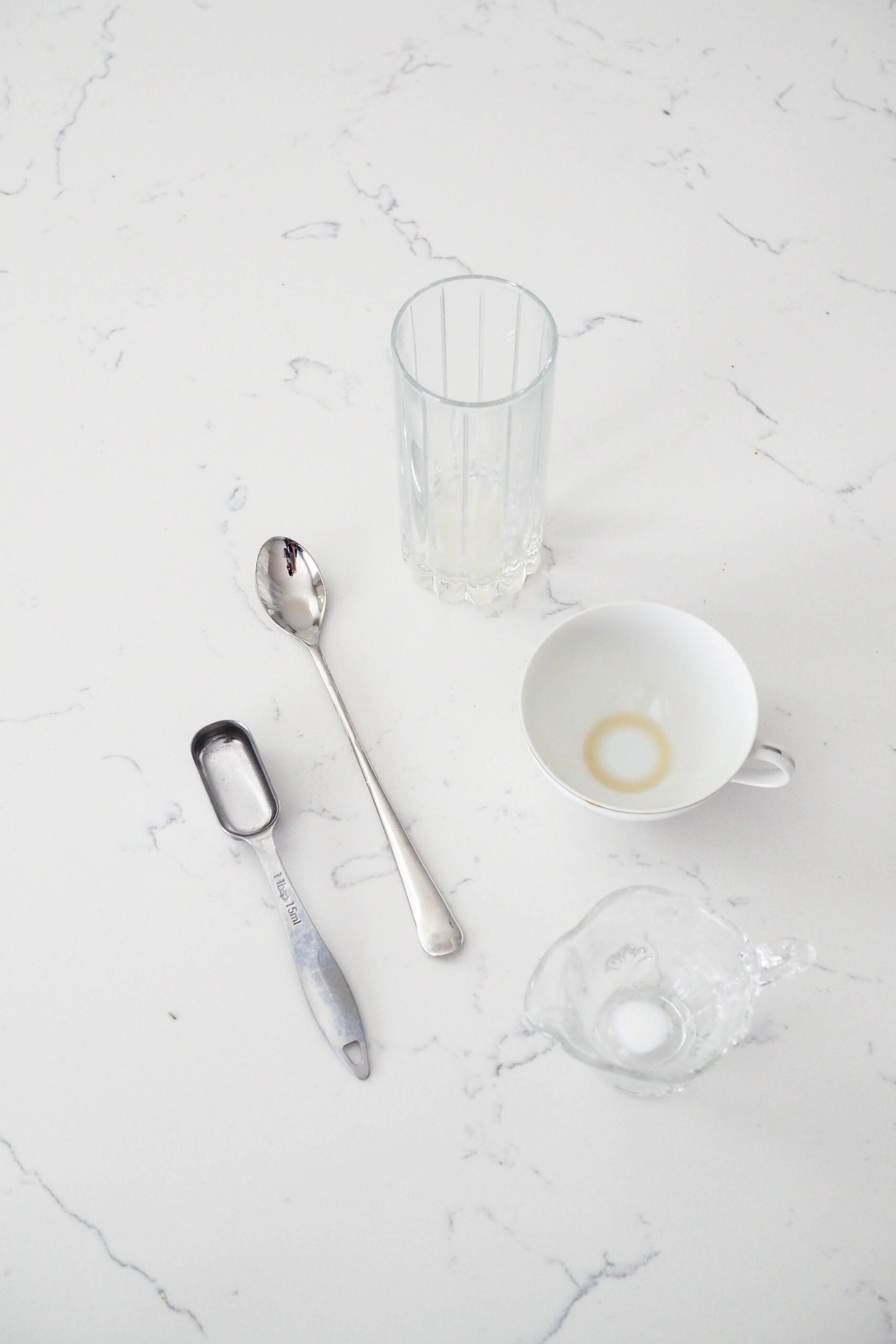 Three cups and two spoons on a white counter.