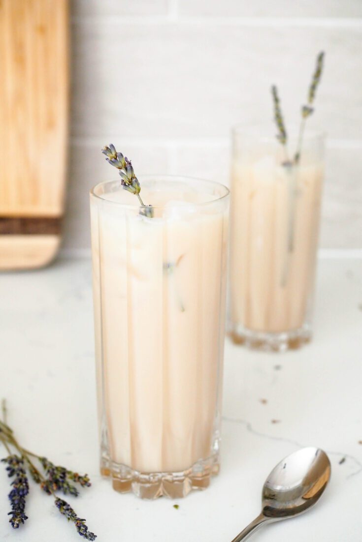 Two highball glasses filled with ice and Earl grey lattes, topped with lavender sprigs.