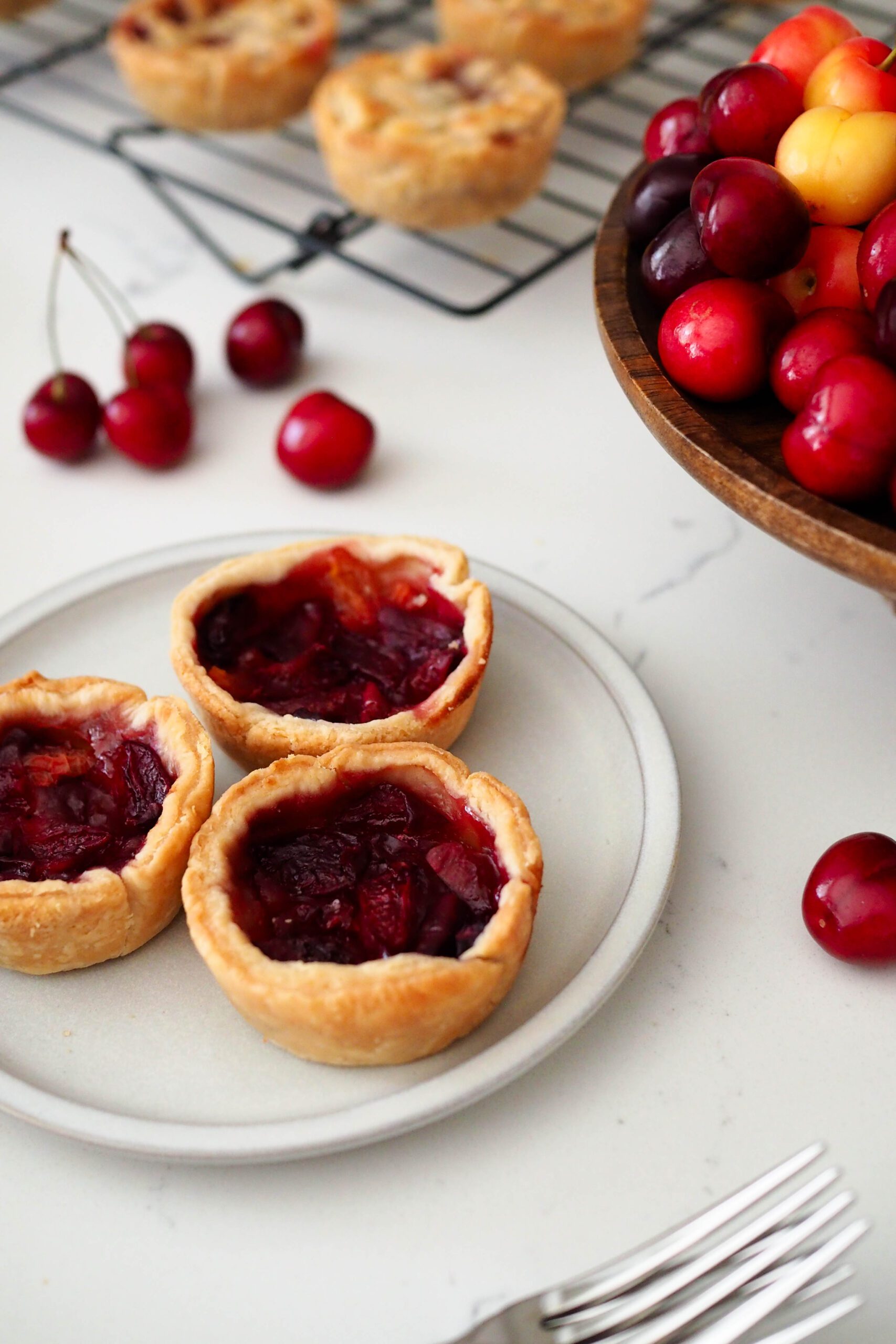 Three mini cherry pies without lattices on a plate.