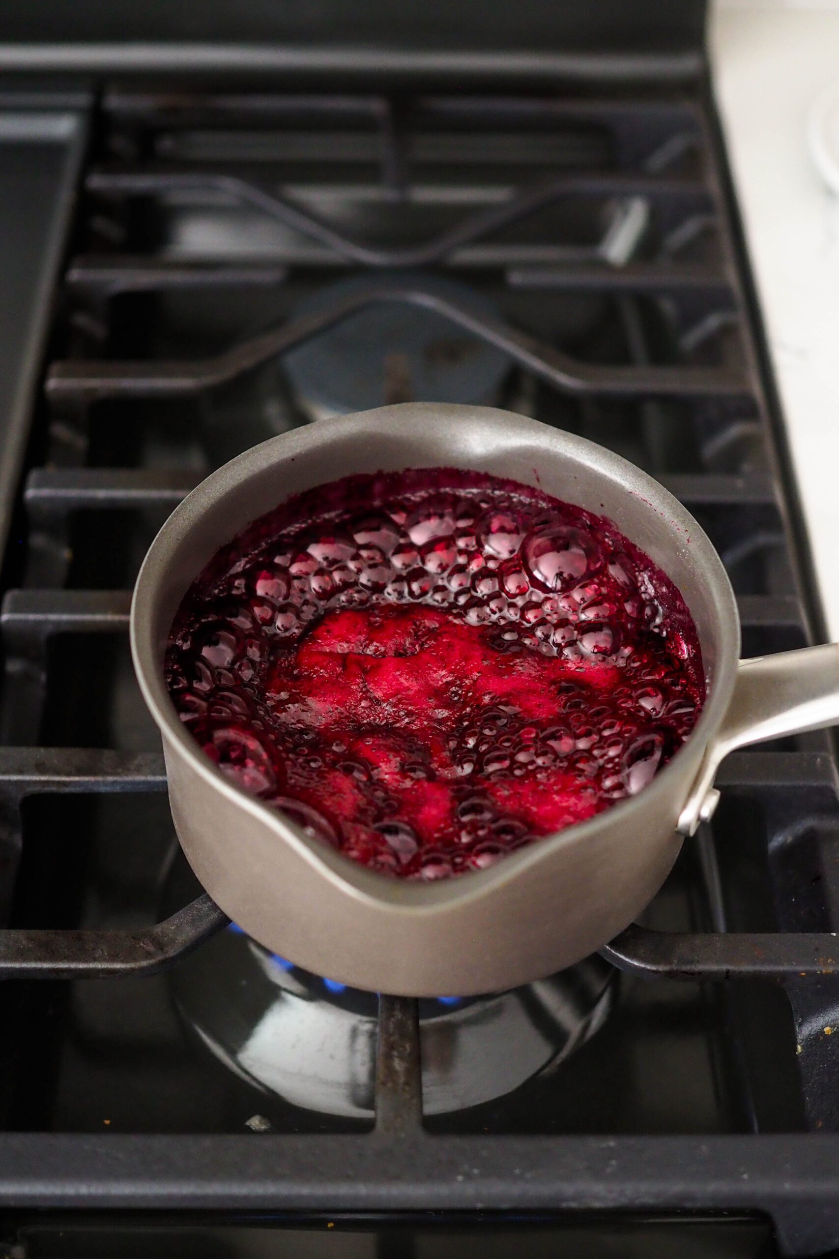 Blueberries boiling in a small pot over the stove.