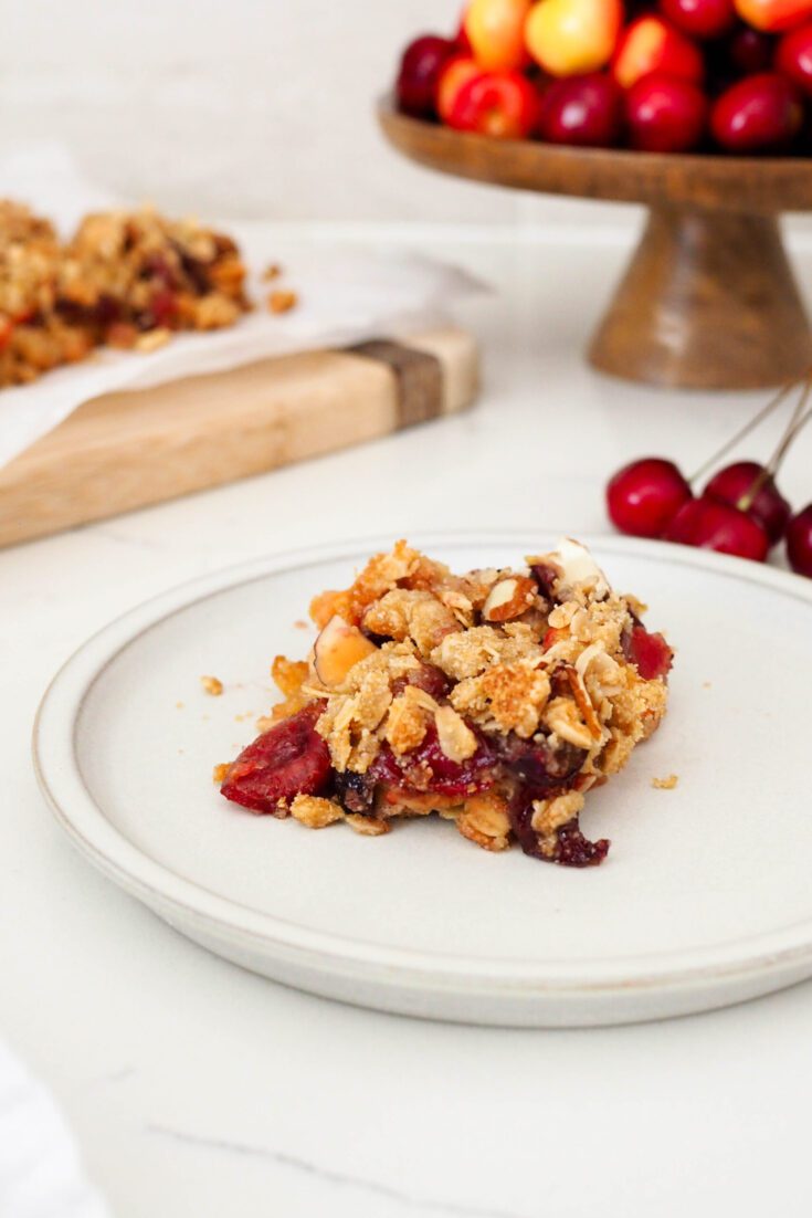 A closeup of a bar of gluten-free cherry almond crumble on a plate.