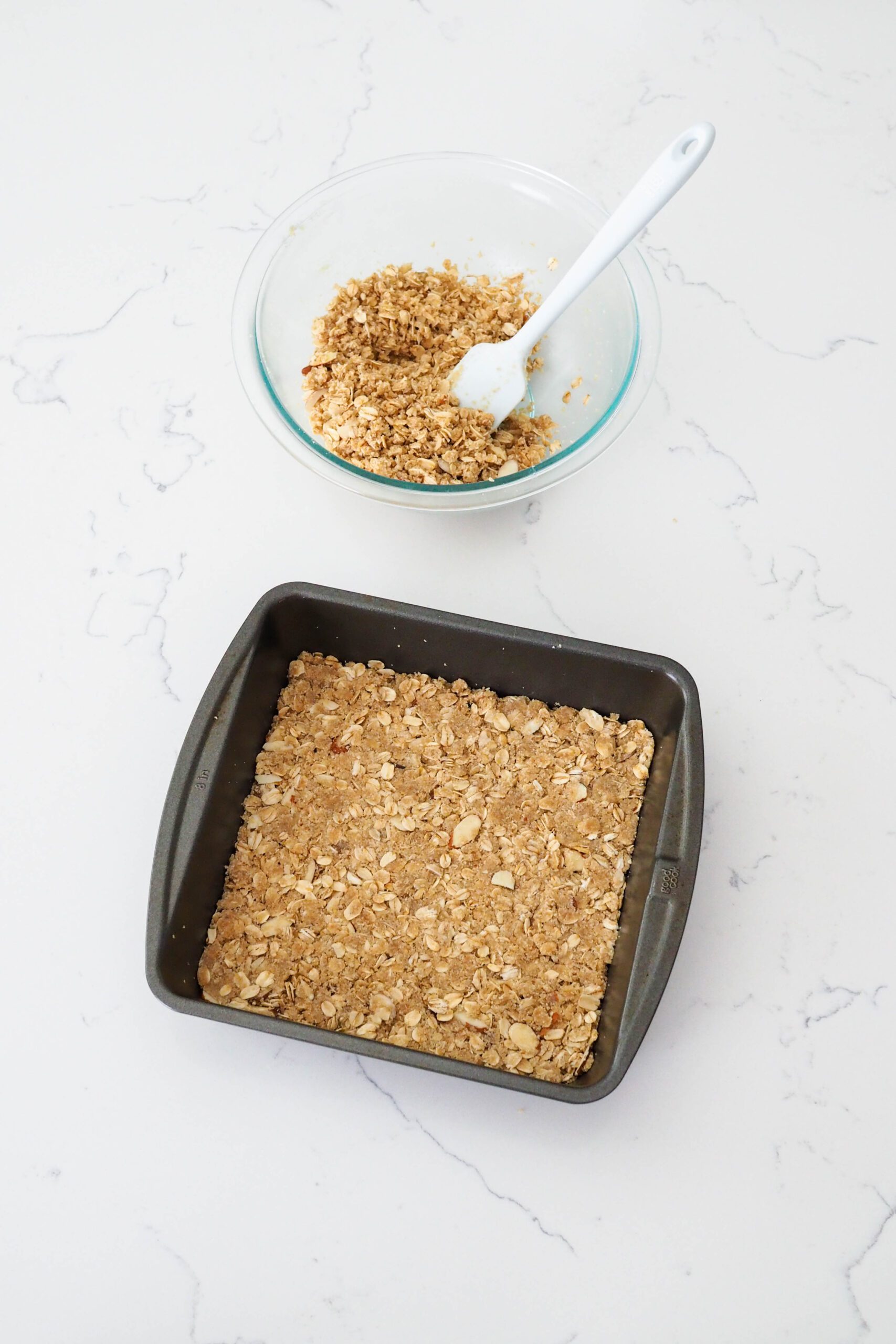 A square pan with gluten-free crumble pressed into the bottom.