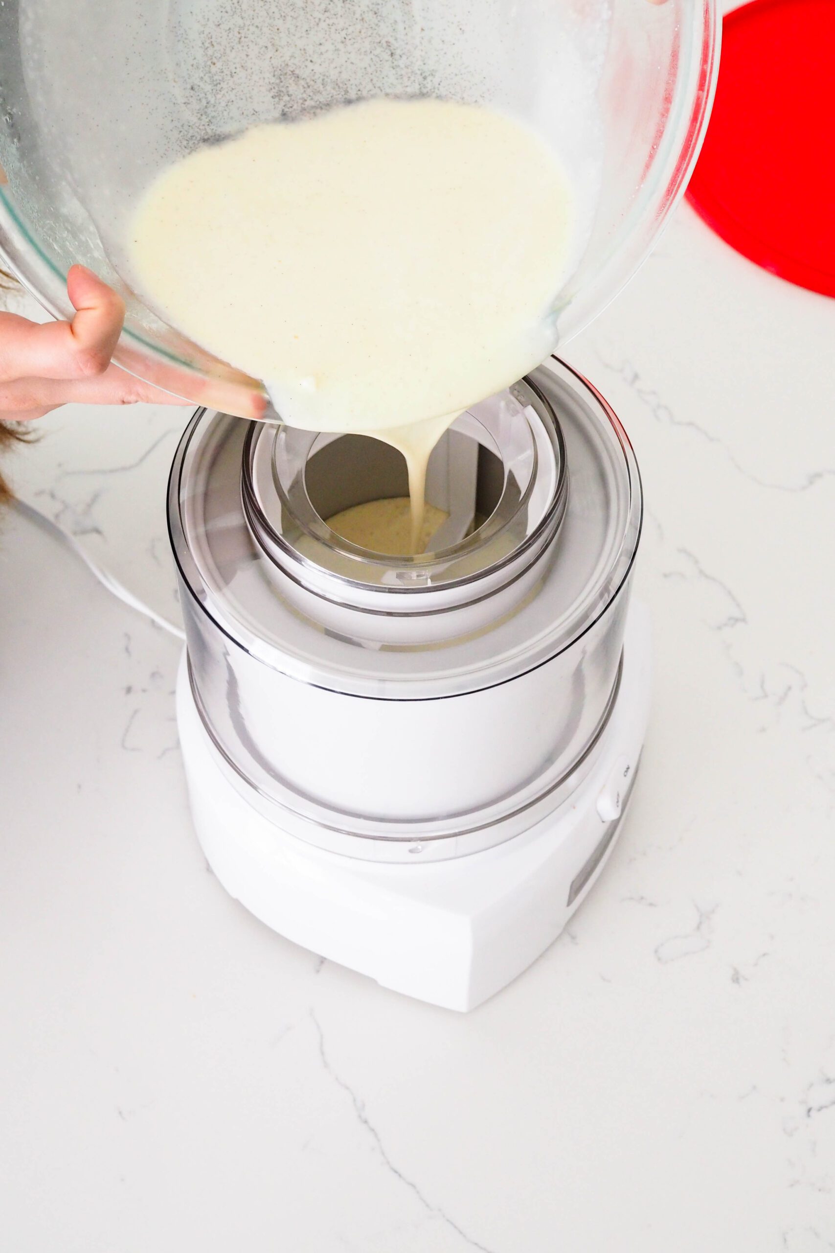 Two hands pour French vanilla ice cream base into an ice cream maker.