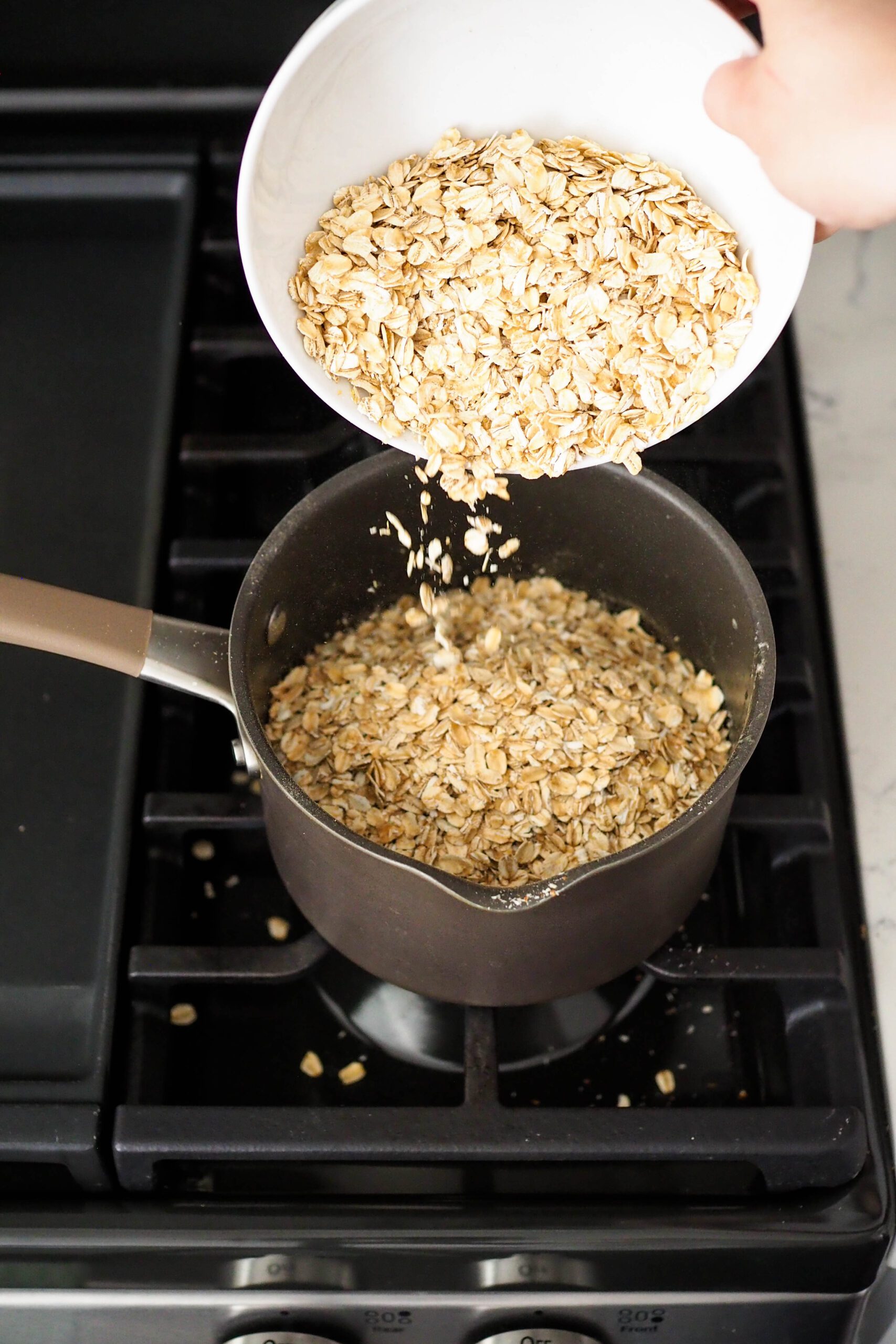 Rolled oats are poured into a medium pot over the stove.