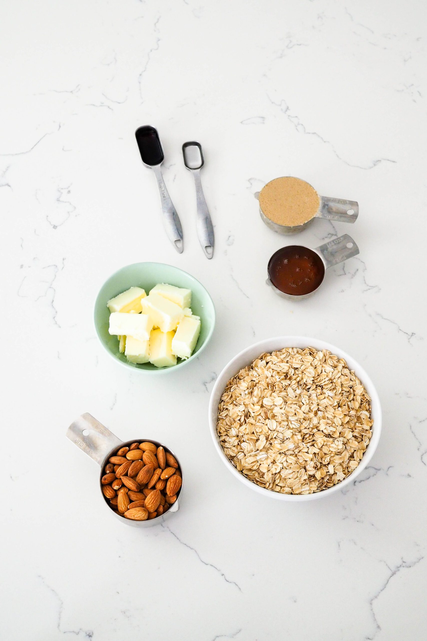 Ingredients for vanilla almond granola on a quartz countertop.