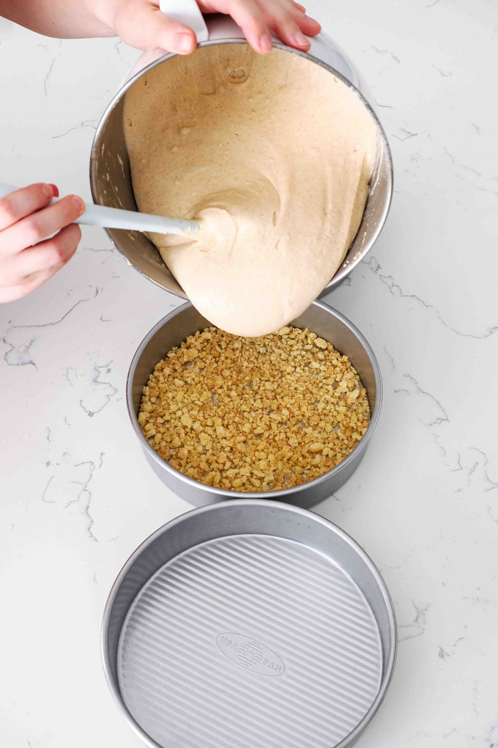 Cinnamon cake batter is poured into 8-inch cake pans.